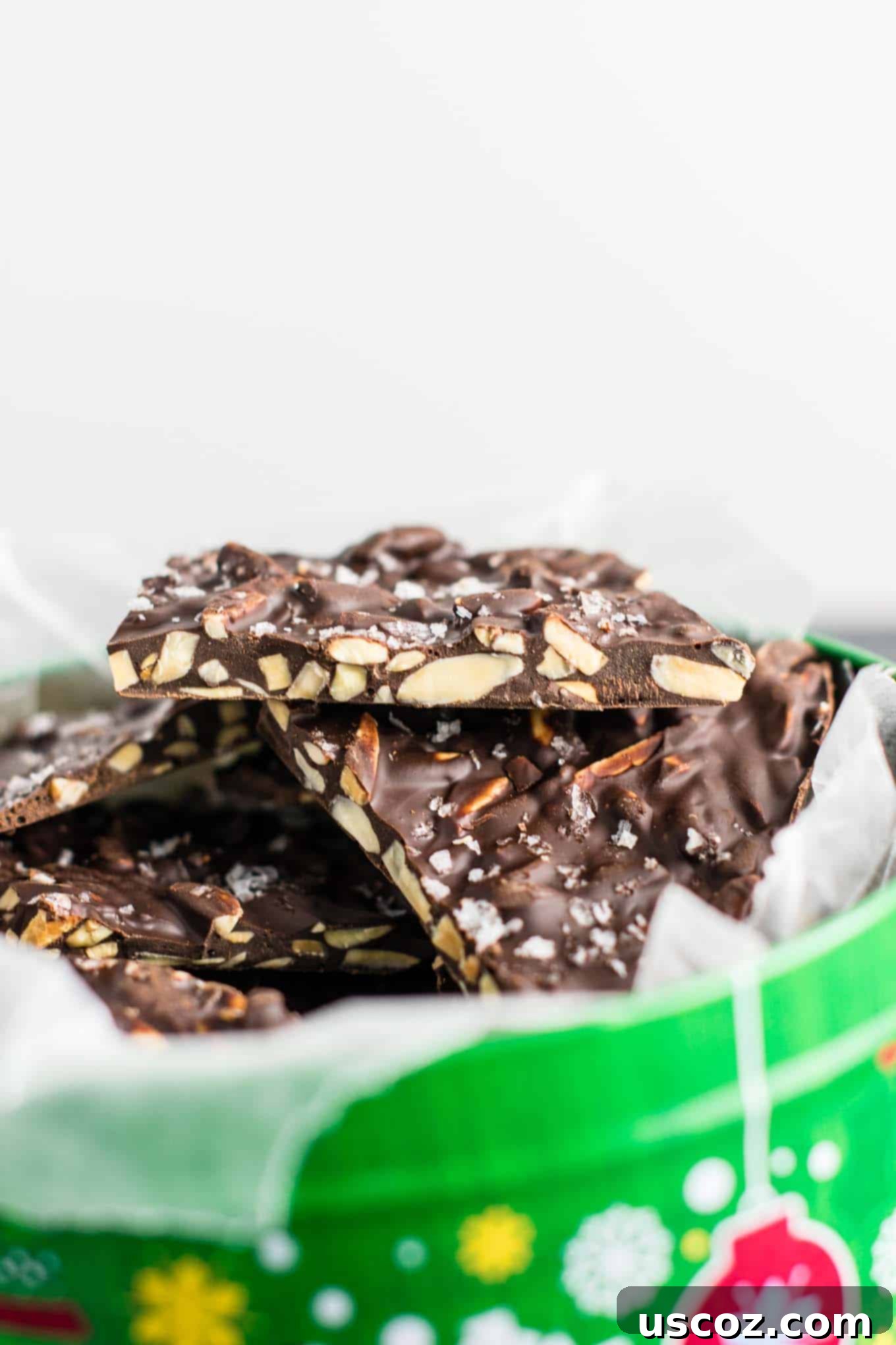Decadent Dark Chocolate Almond Bark 7 A close-up of a broken piece of dark chocolate almond bark, revealing the embedded slivered almonds and the glossy texture of the chocolate.