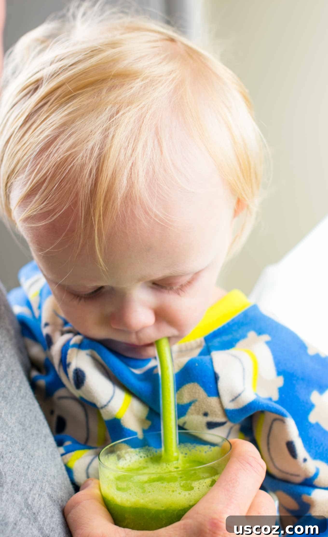 Vibrant Citrus Kale Green Smoothie 9 toddler taking a drink of green smoothie from a glass