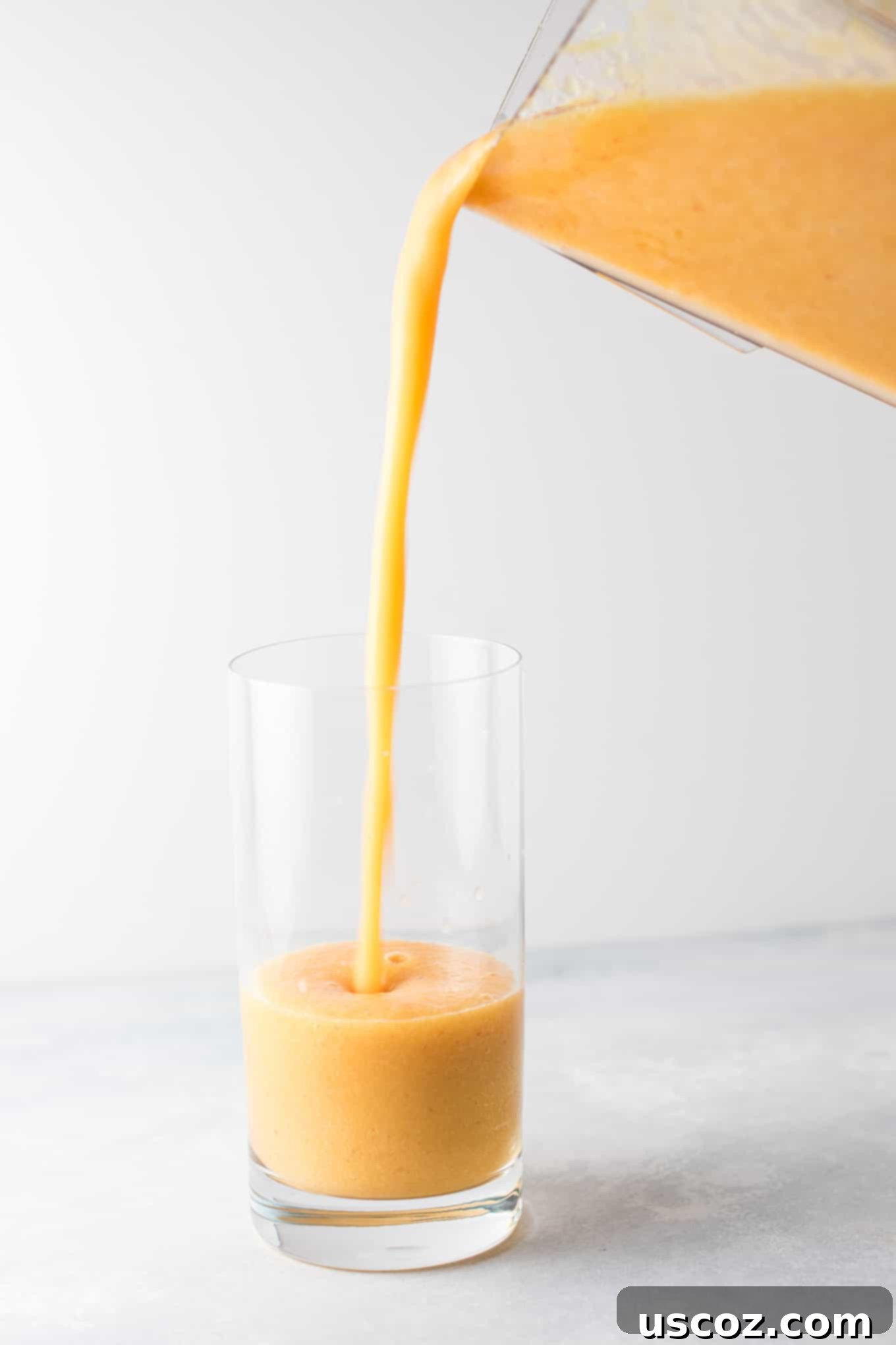 A glass of Ginger Peach Detox Smoothie on a bright background, garnished with a slice of peach. A perfect healthy beverage for a quick meal or snack. #healthysmoothie #detoxsmoothie #gingerpeachsmoothie #vegan #smoothierecipes