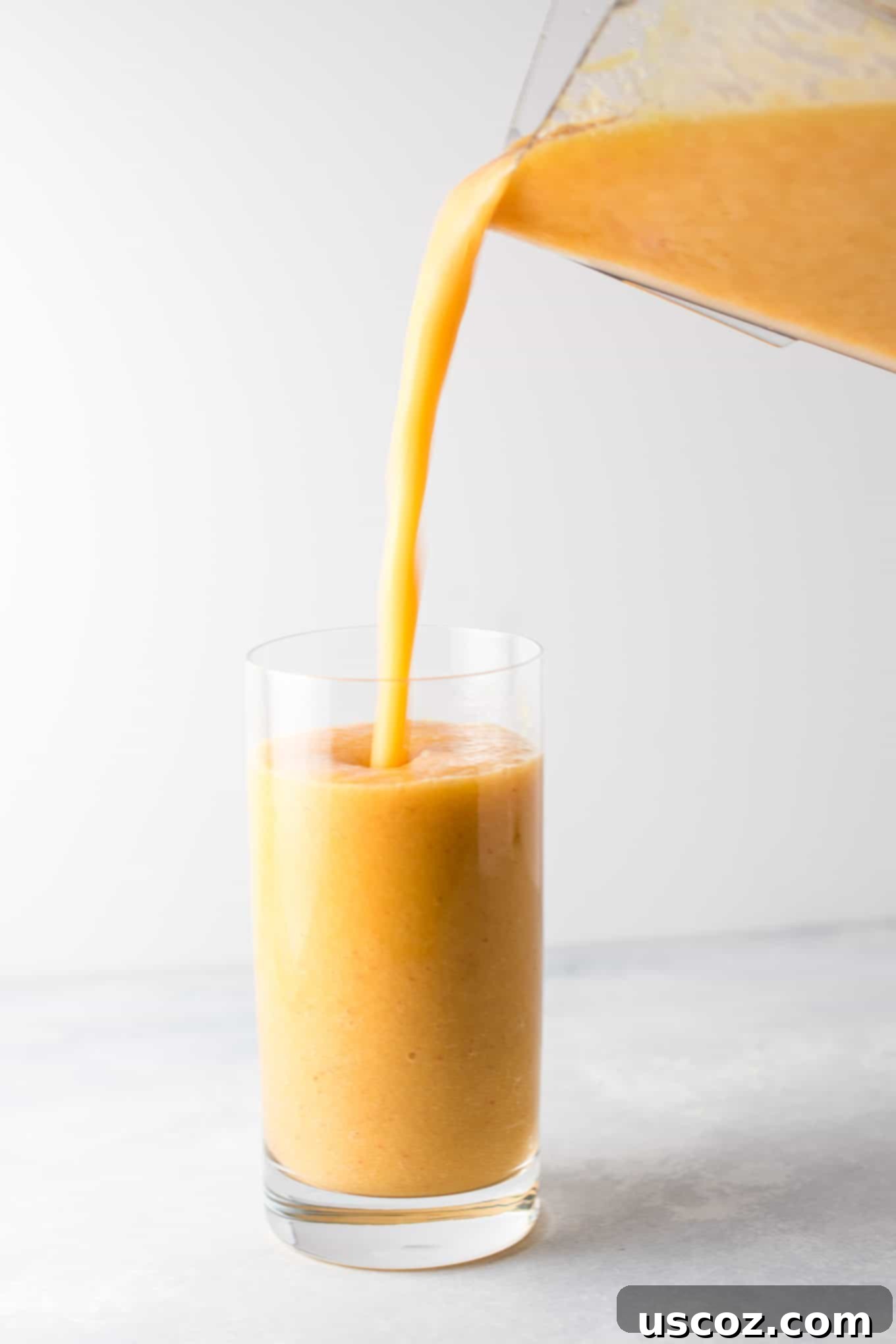 Close-up of a child's hand holding a glass of Ginger Peach Detox Smoothie. A great way to get healthy nutrients into picky eaters. #healthysmoothie #detoxsmoothie #gingerpeachsmoothie #vegan #smoothierecipes