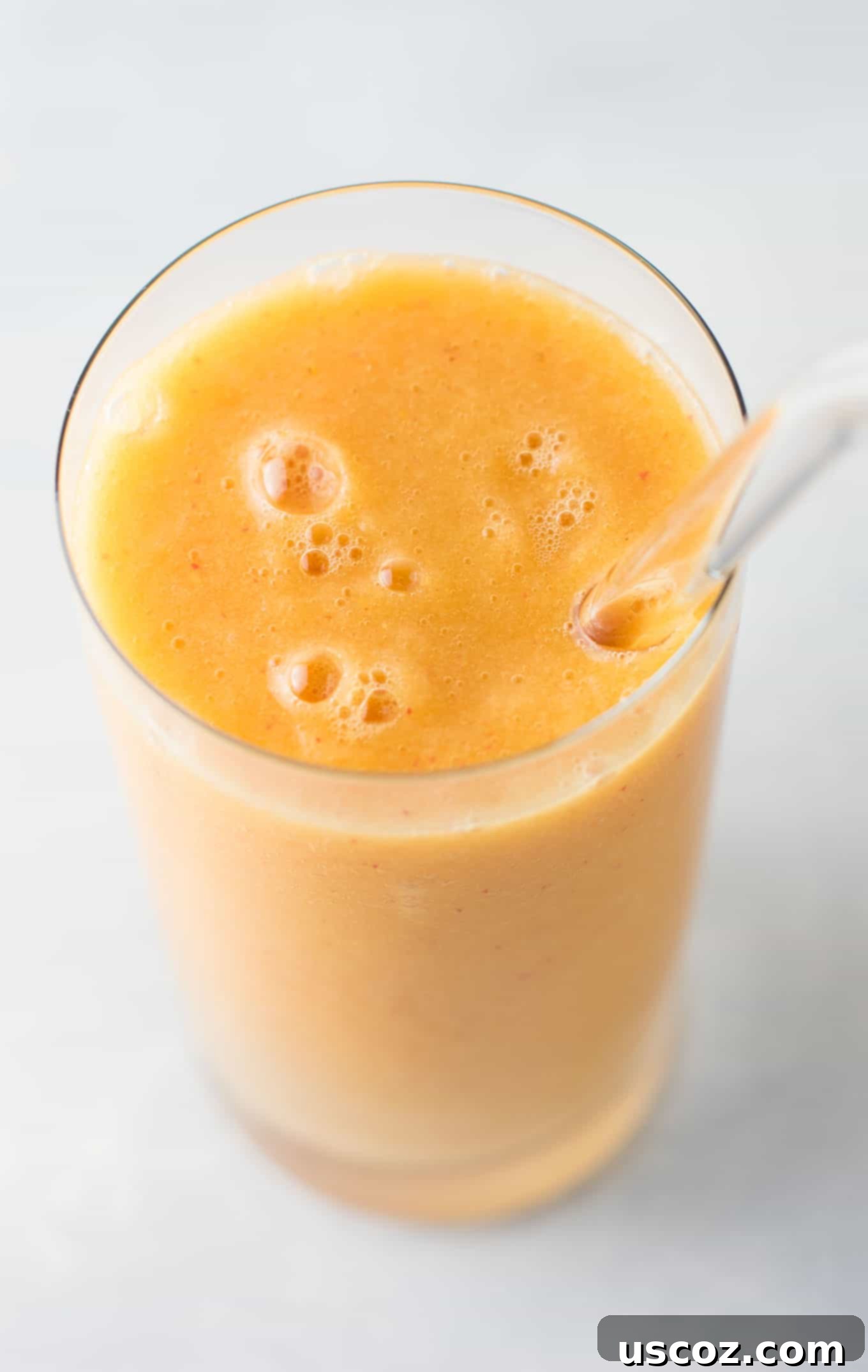 Overhead shot of two glasses of Ginger Peach Detox Smoothie with fresh ginger and peach slices nearby. Emphasizing fresh ingredients and health. #healthysmoothie #detoxsmoothie #gingerpeachsmoothie #vegan #smoothierecipes