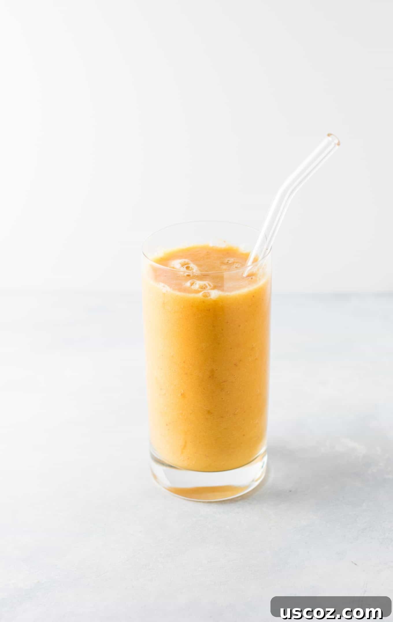 Top-down view of a glass of Ginger Peach Detox Smoothie with fresh ingredients around it. Highlighting a healthy lifestyle. #healthysmoothie #detoxsmoothie #gingerpeachsmoothie #vegan #smoothierecipes