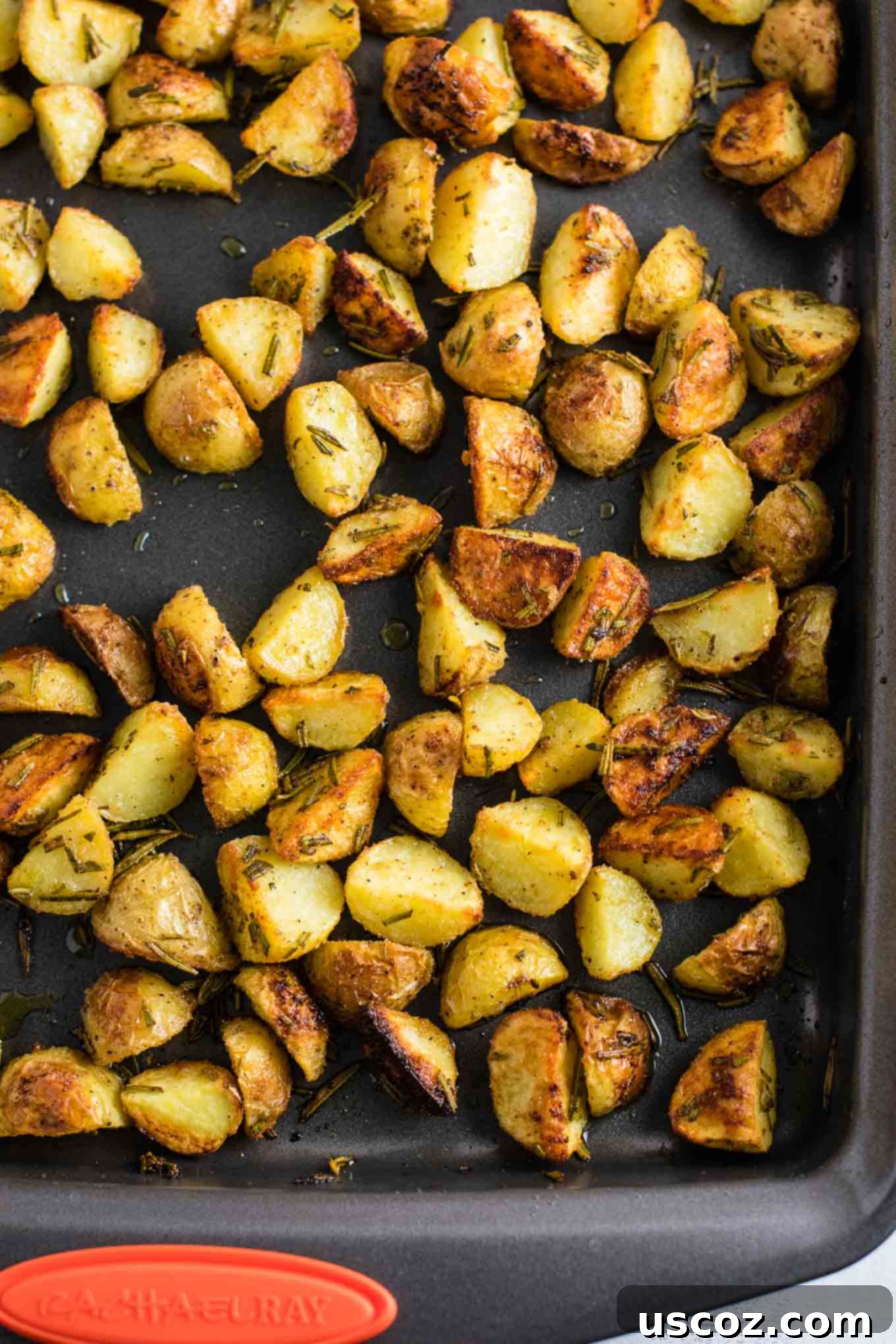 A rustic wooden board showcasing a generous portion of freshly roasted baby potatoes, beautifully seasoned with fresh rosemary and spices, accompanied by a small pile of unchopped rosemary sprigs.