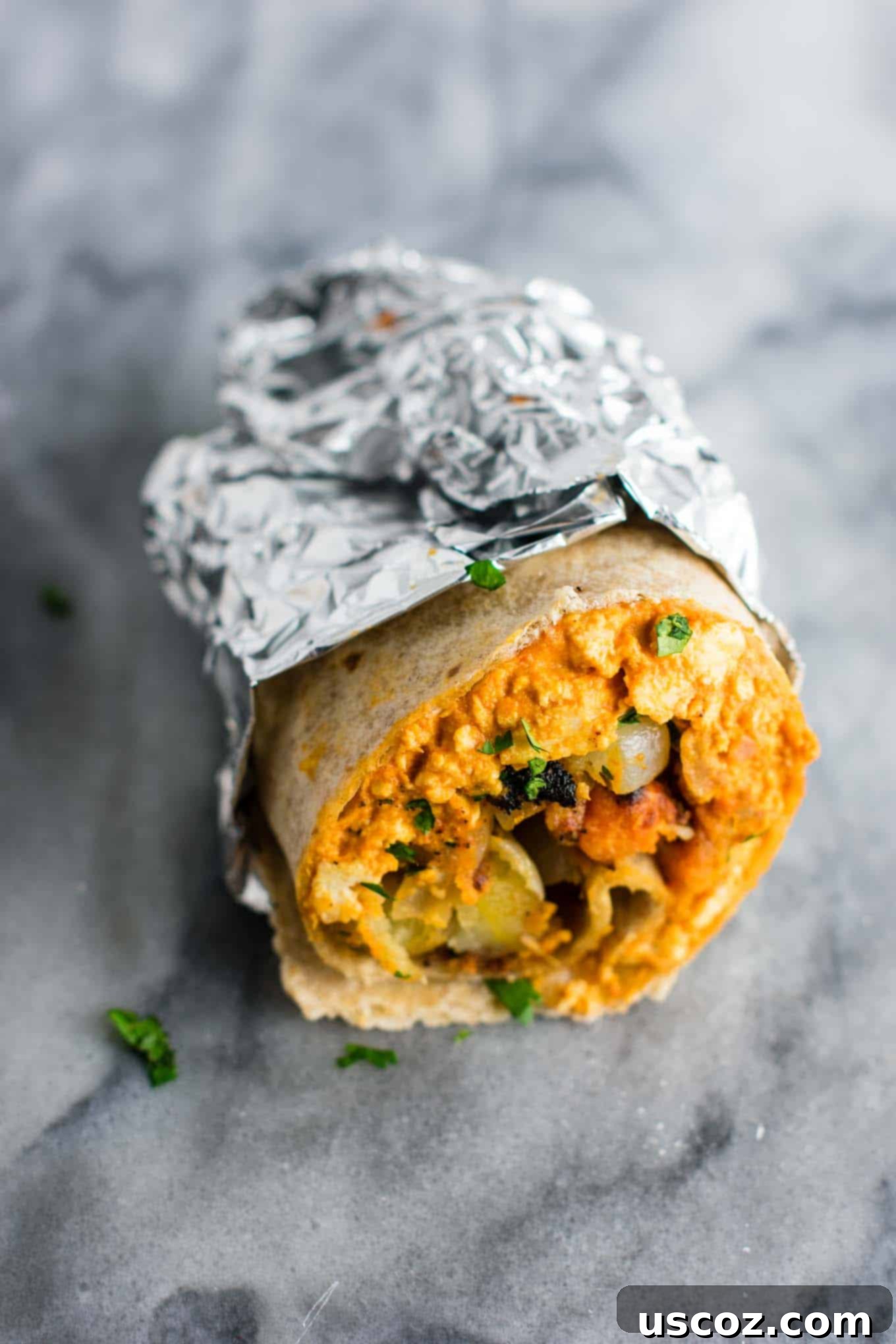 Plant-Based Breakfast Burrito Bliss 14 A vegan breakfast burrito, half-wrapped in foil, showing the filling.