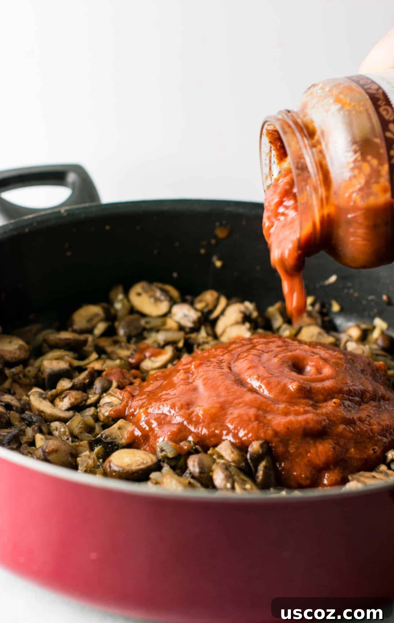 Delicious Vegetarian Spaghetti Sauce 10 pasta sauce being poured into the skillet with the mushrooms
