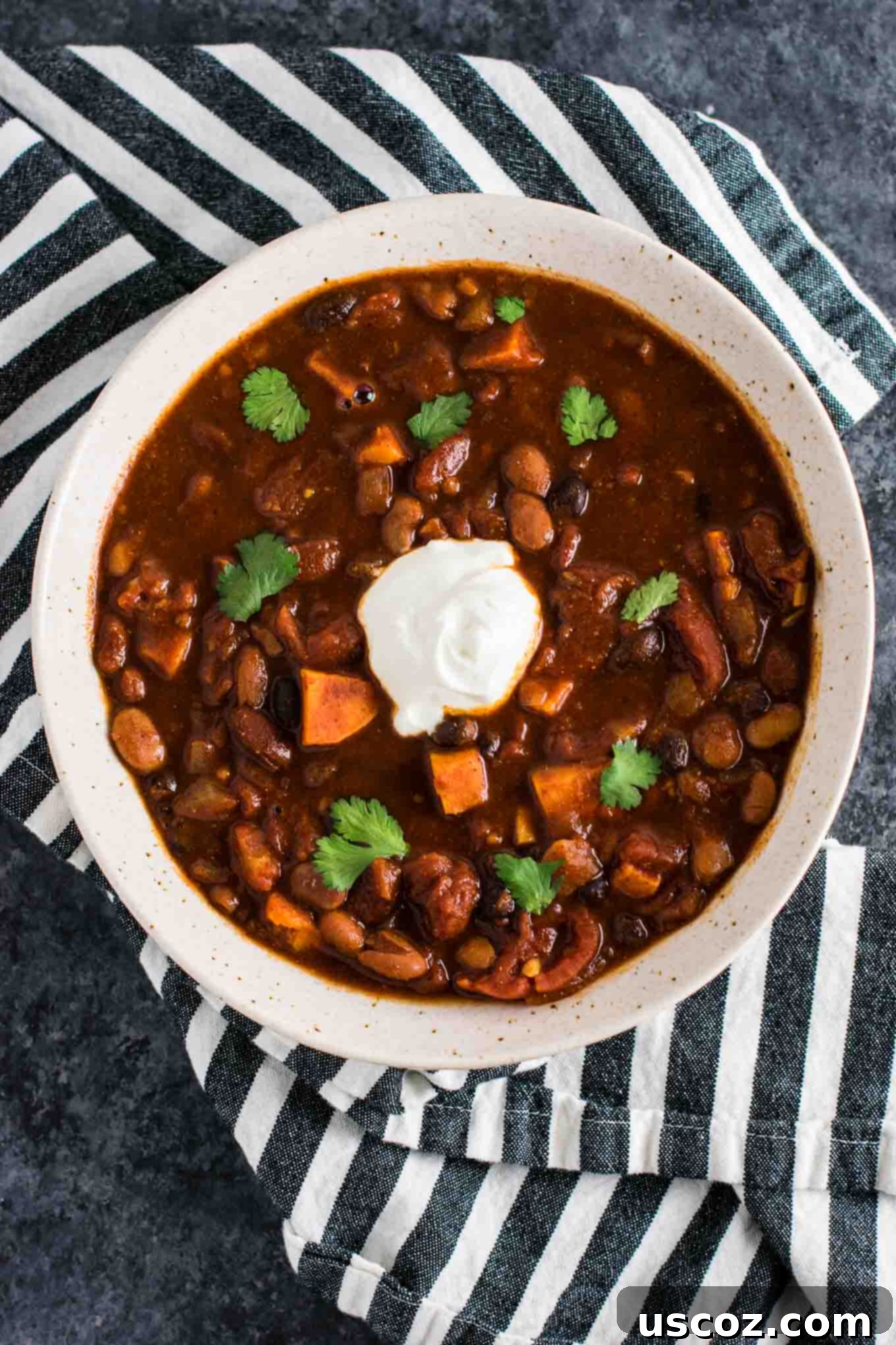 Easy Slow Cooker Vegetarian Sweet Potato Chili 2 A vibrant bowl of Slow Cooker Vegetarian Sweet Potato Chili topped with fresh cilantro and a dollop of sour cream, ready to be enjoyed.