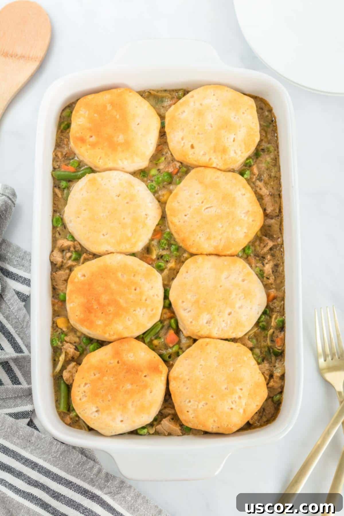 Garden Harvest Pie 11 A large casserole dish filled with creamy veggie pot pie filling, generously topped with multiple golden-brown, flaky biscuits, ready to be served.