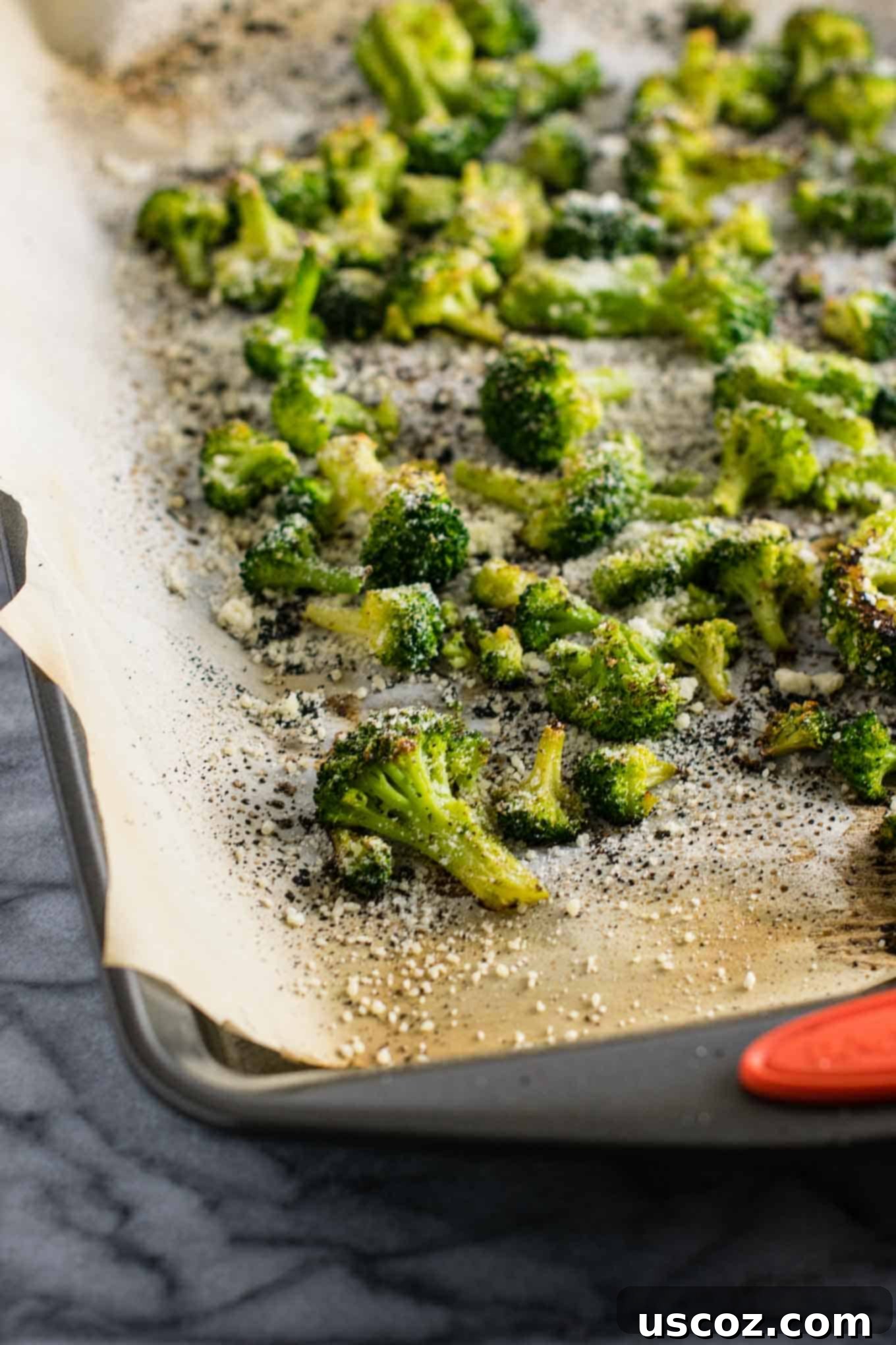 Perfectly Roasted Frozen Broccoli 3 Finished roasted frozen broccoli with crispy edges on a parchment-lined baking sheet.