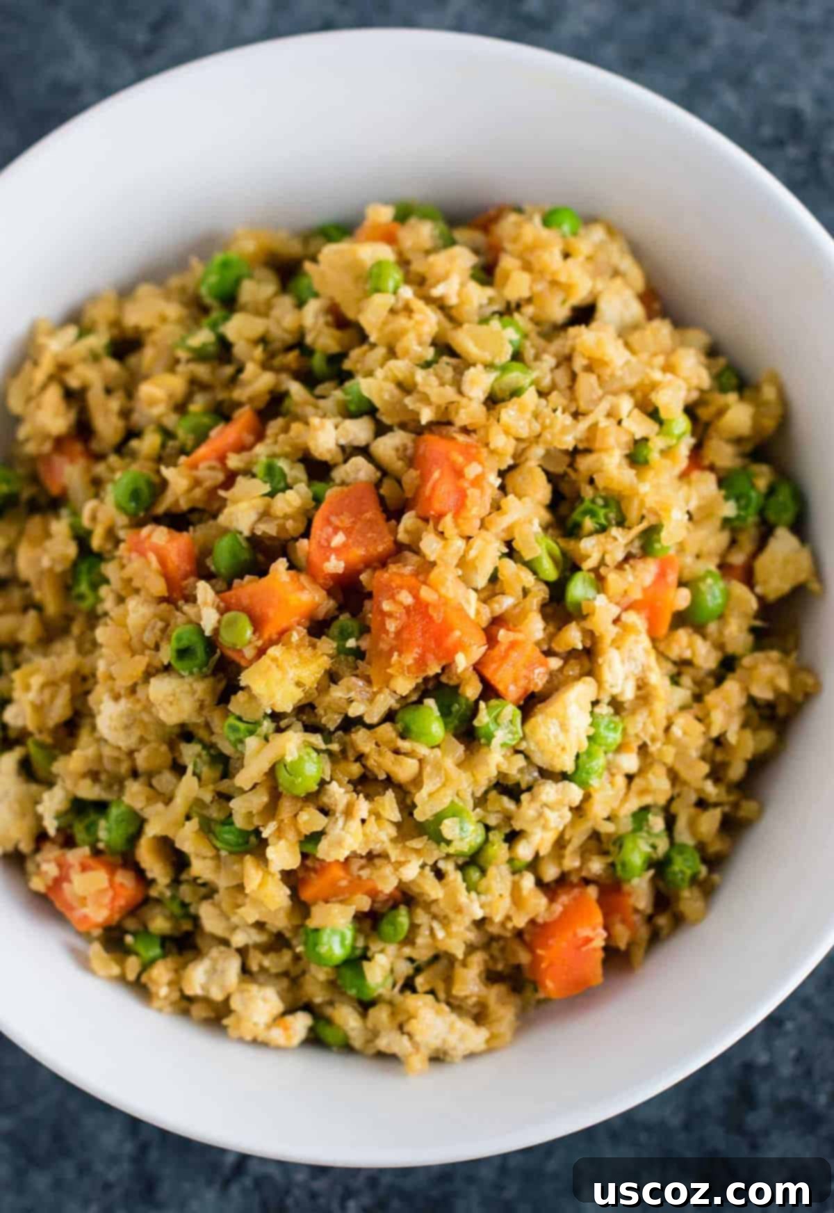 Wholesome Cauliflower Tofu Fried Rice 2 A vibrant bowl of vegan cauliflower tofu fried rice, showcasing riced cauliflower, crumbled tofu, and colorful vegetables like carrots and peas. Ideal for a healthy, gluten-free, and grain-free dinner.