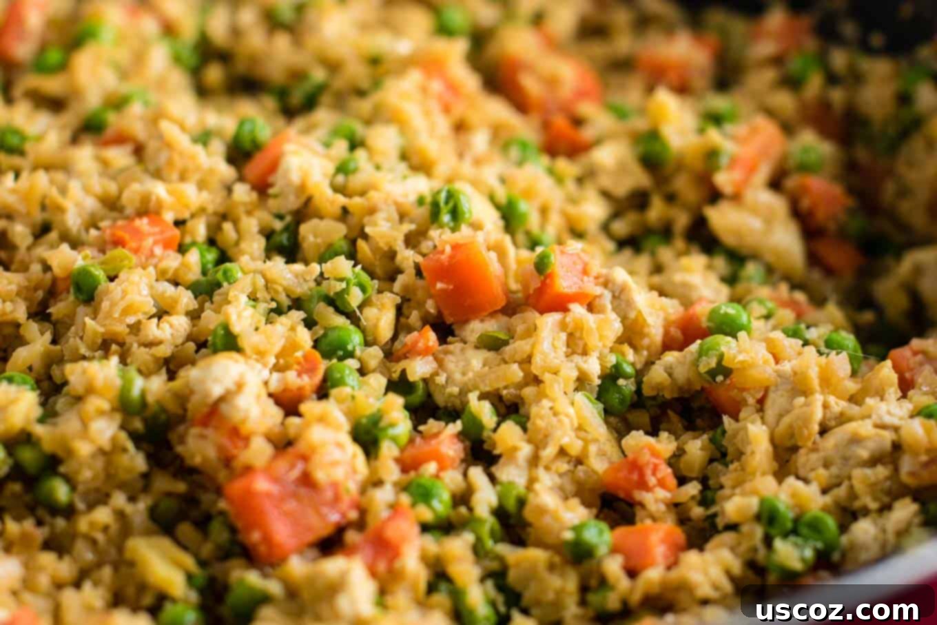 Wholesome Cauliflower Tofu Fried Rice 3 Close-up view of freshly cooked Cauliflower Tofu Fried Rice, highlighting the texture of scrambled tofu and riced cauliflower, mixed with green peas and carrots.