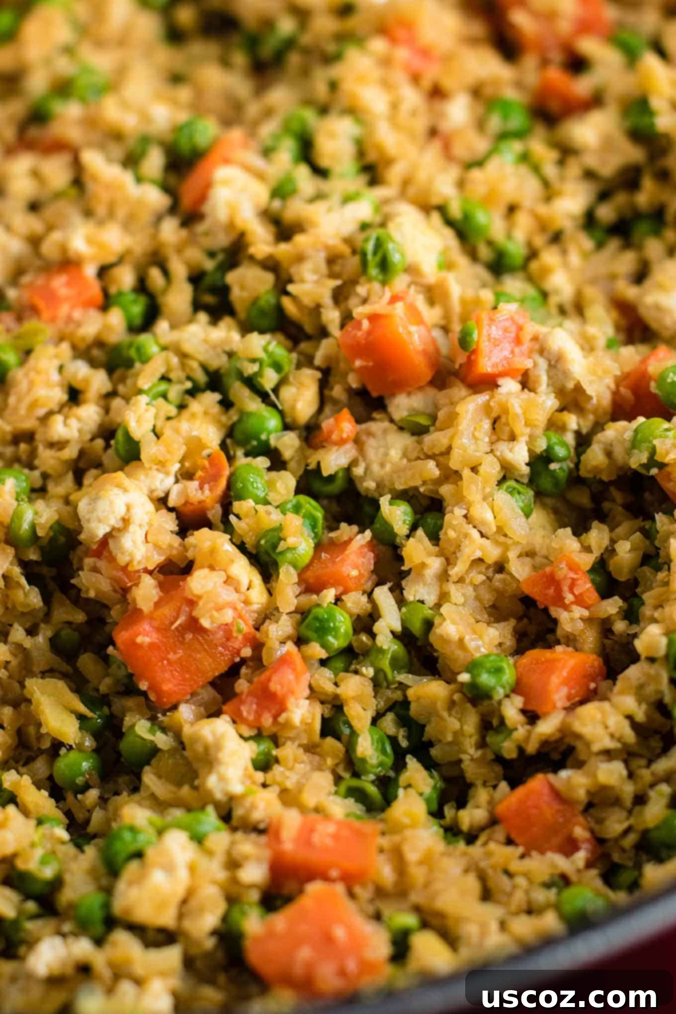 Wholesome Cauliflower Tofu Fried Rice 4 A large serving spoon scooping up a portion of the delicious Cauliflower Tofu Fried Rice from a skillet, showing the well-mixed ingredients and inviting texture.