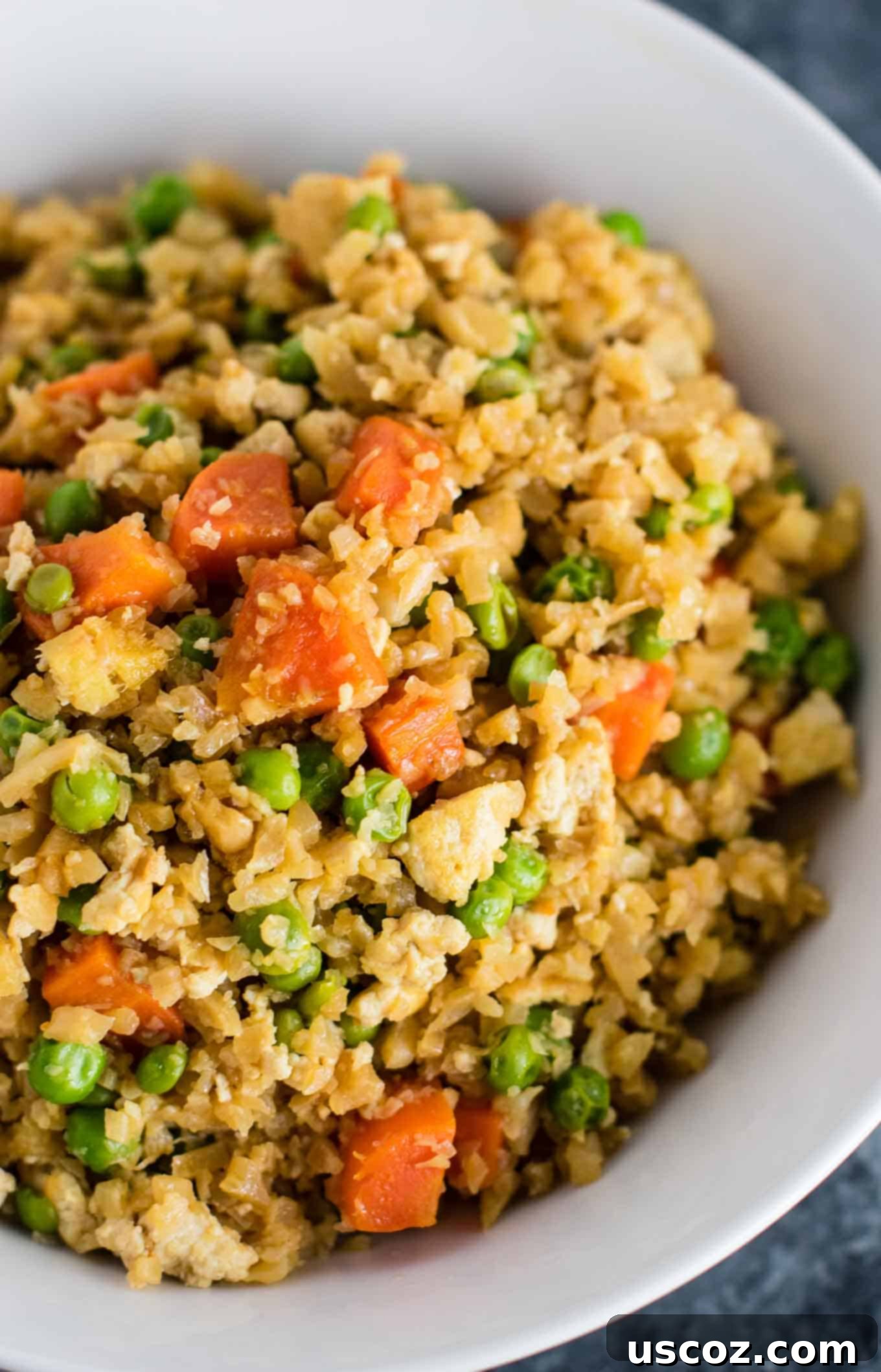 Wholesome Cauliflower Tofu Fried Rice 9 A close-up shot of the finished Cauliflower Tofu Fried Rice, showcasing the colorful mix of cauliflower, tofu, carrots, and peas in a well-seasoned, healthy dish.