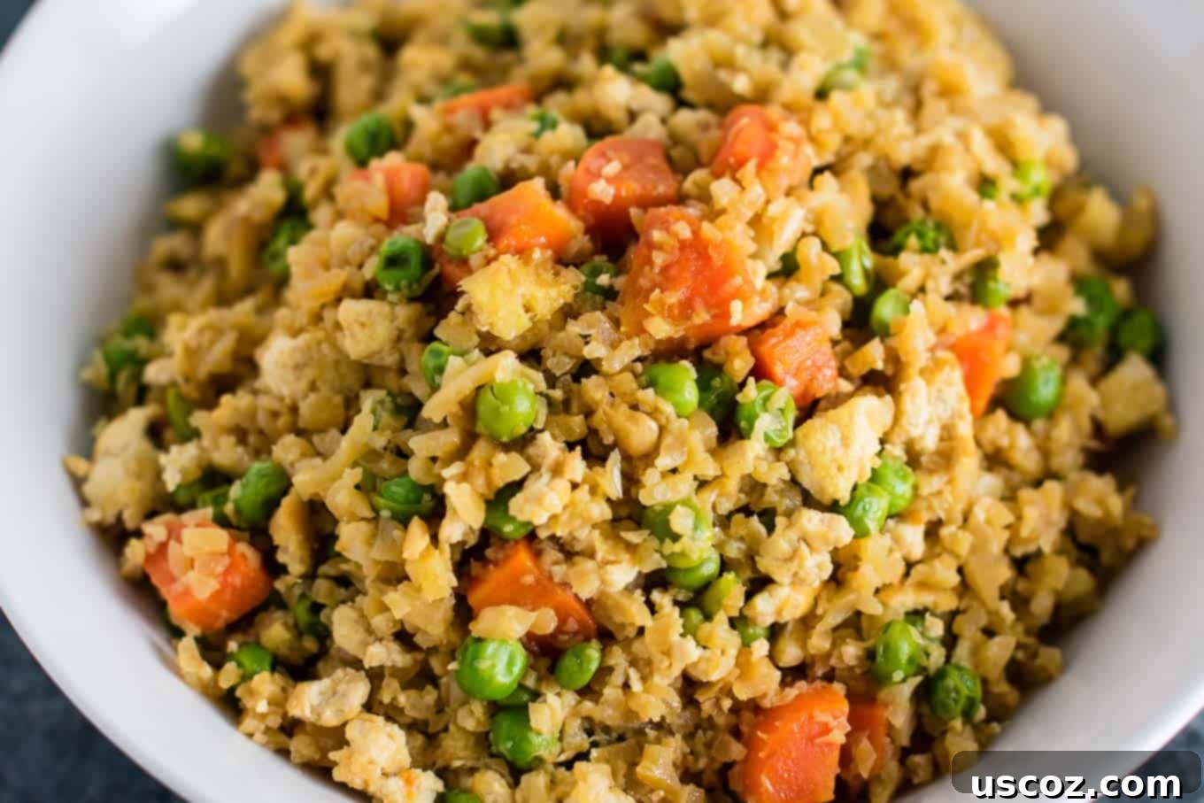Wholesome Cauliflower Tofu Fried Rice 10 A delicious and healthy vegan cauliflower tofu fried rice in a large bowl, ready to be served. This dish is rich in flavor from fresh ginger, garlic, carrots, and peas.