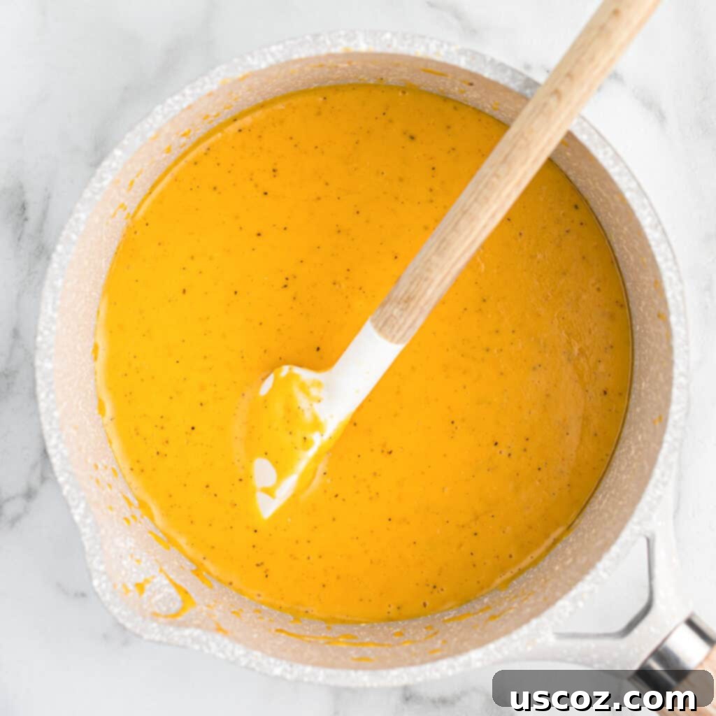 Ultimate Cheesy Broccoli Sauce 6 Cheese sauce for broccoli being stirred in a sauce pan, showcasing its creamy texture
