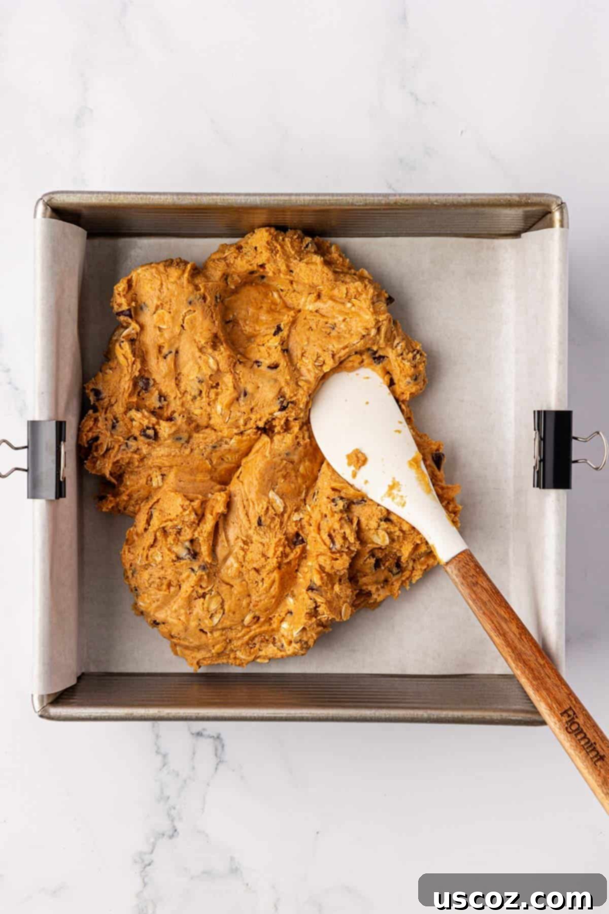 PB & Chocolate Chip Protein Bars 7 Spreading the protein bar batter into an 8x8 baking dish lined with parchment paper.