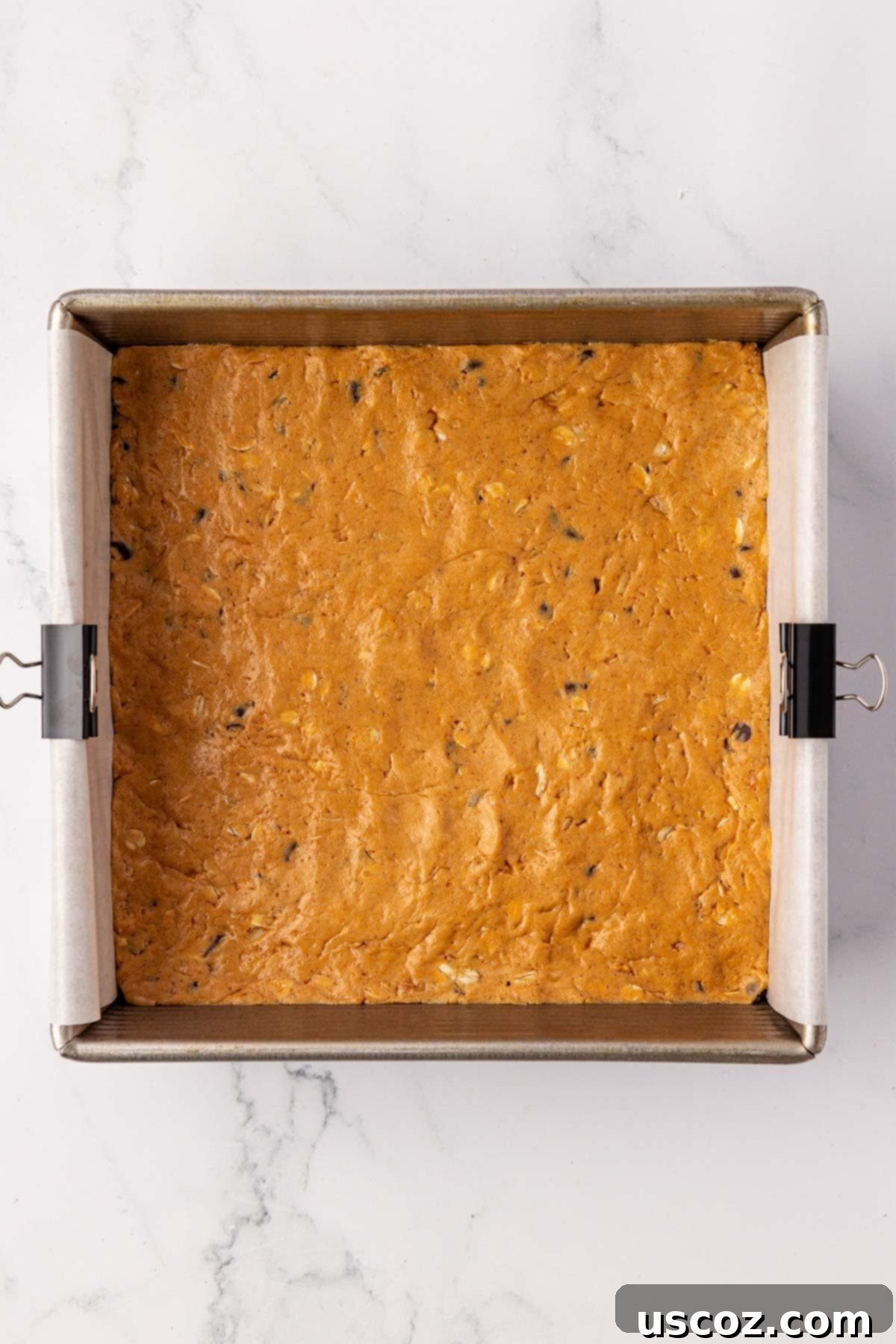 PB & Chocolate Chip Protein Bars 9 Protein bar batter neatly pressed into a lined baking dish, before topping.