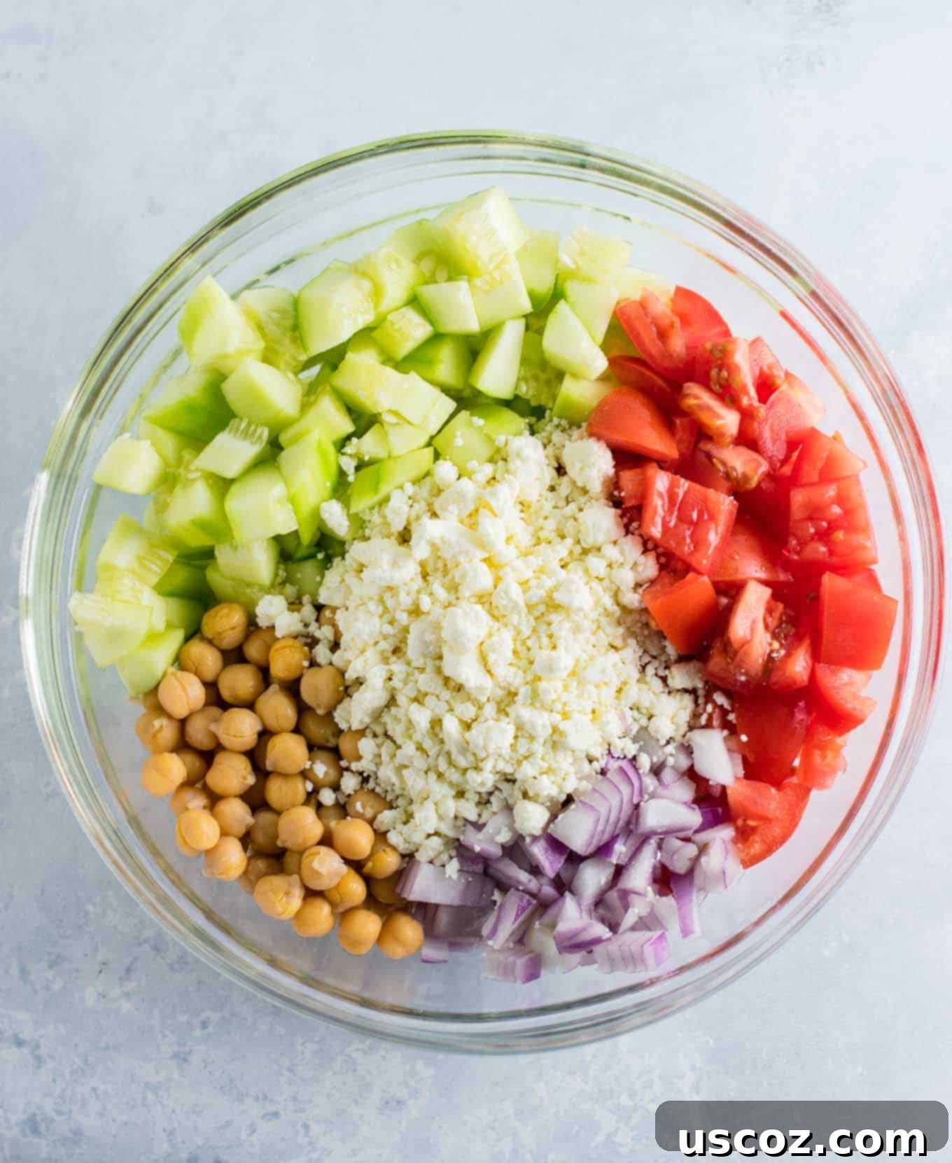 Tangy Greek Cucumber Delight 3 ingredients in a bowl before mixing - cucumbers, feta cheese, red onion, tomatoes, and chickpeas
