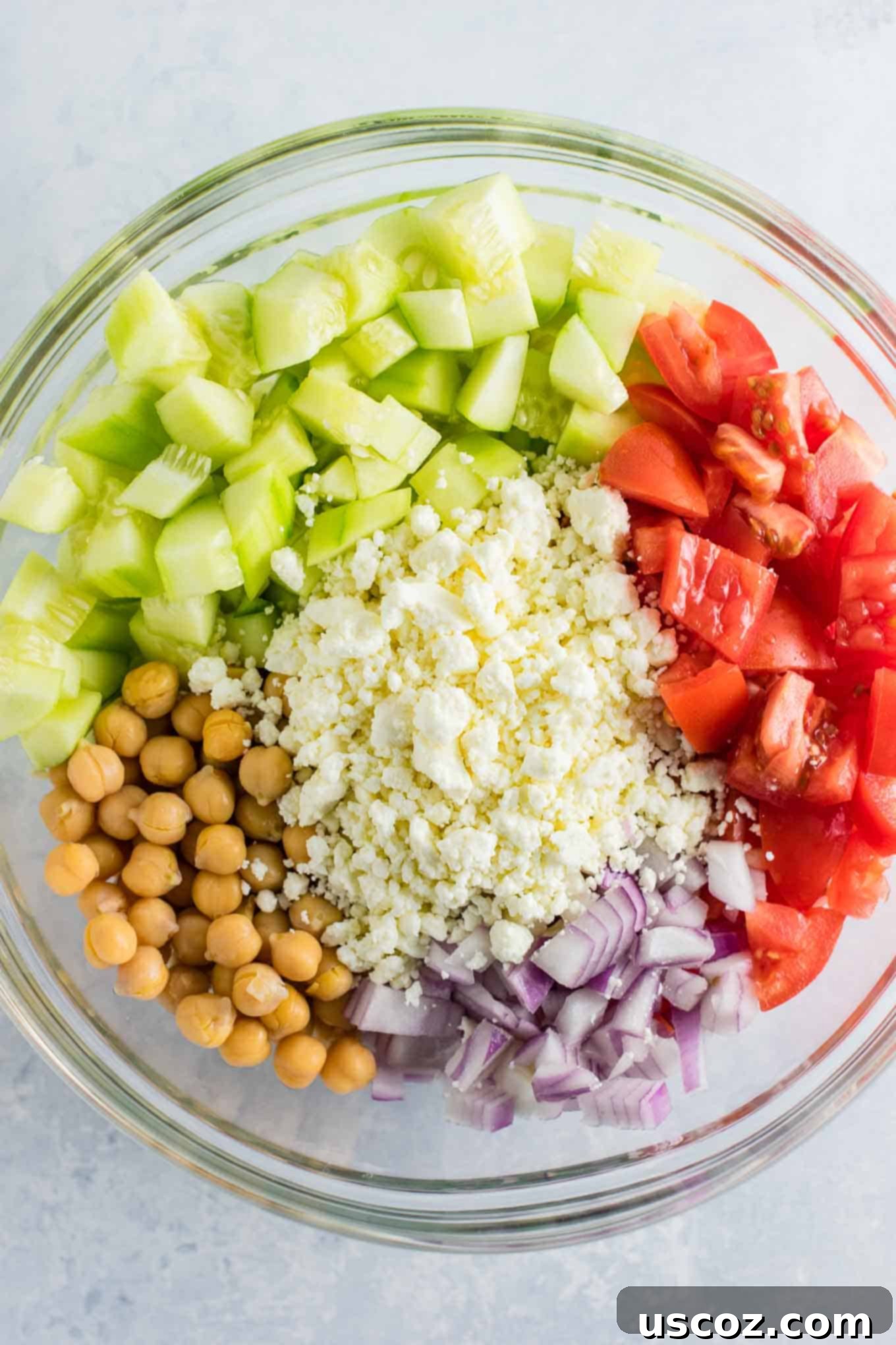 Tangy Greek Cucumber Delight 5 ingredients in a bowl before mixing - cucumbers, feta cheese, red onion, tomatoes, and chickpeas