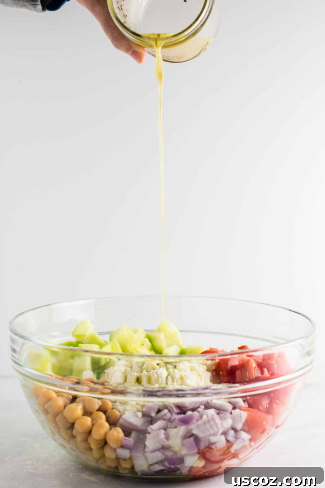 Tangy Greek Cucumber Delight 6 dressing being poured onto the greek salad