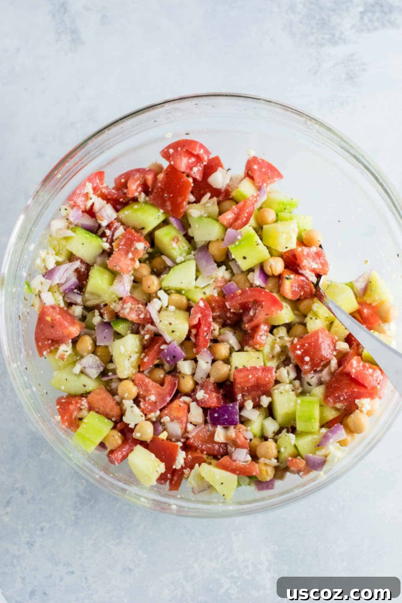Tangy Greek Cucumber Delight 7 greek chickpea salad mixed together in a bowl with a spoon