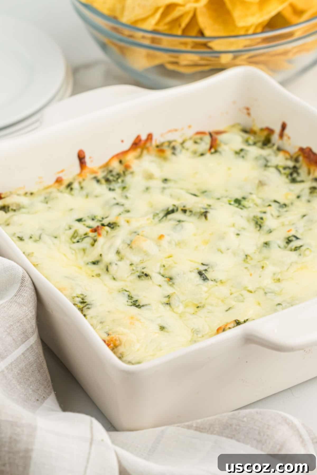 The Ultimate Baked Spinach Artichoke Dip 3 Close-up of baked spinach artichoke dip in a white ceramic dish, hot and bubbling from the oven