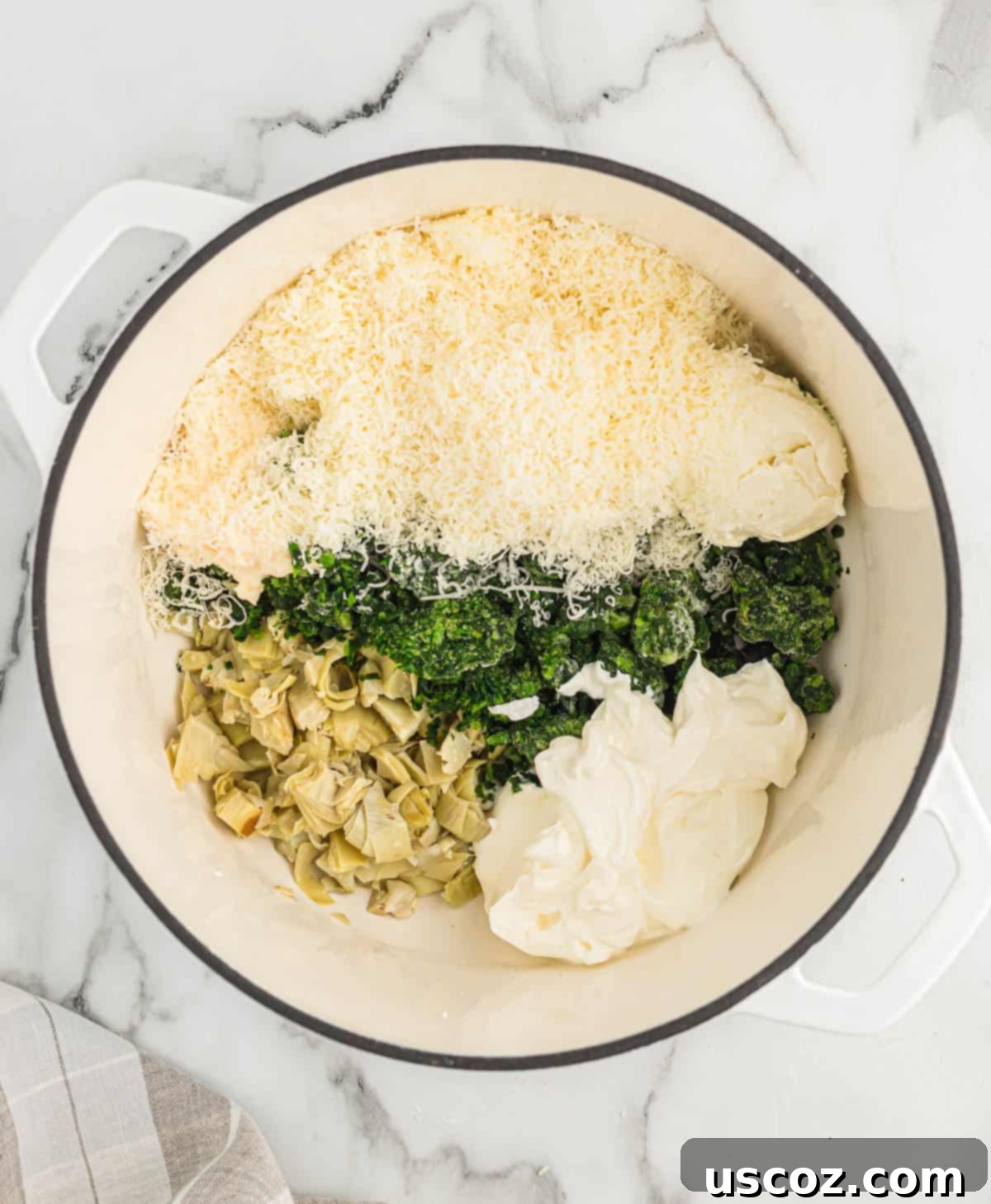 The Ultimate Baked Spinach Artichoke Dip 6 Adding cream cheese, sour cream, and other dip ingredients to a Dutch oven for mixing