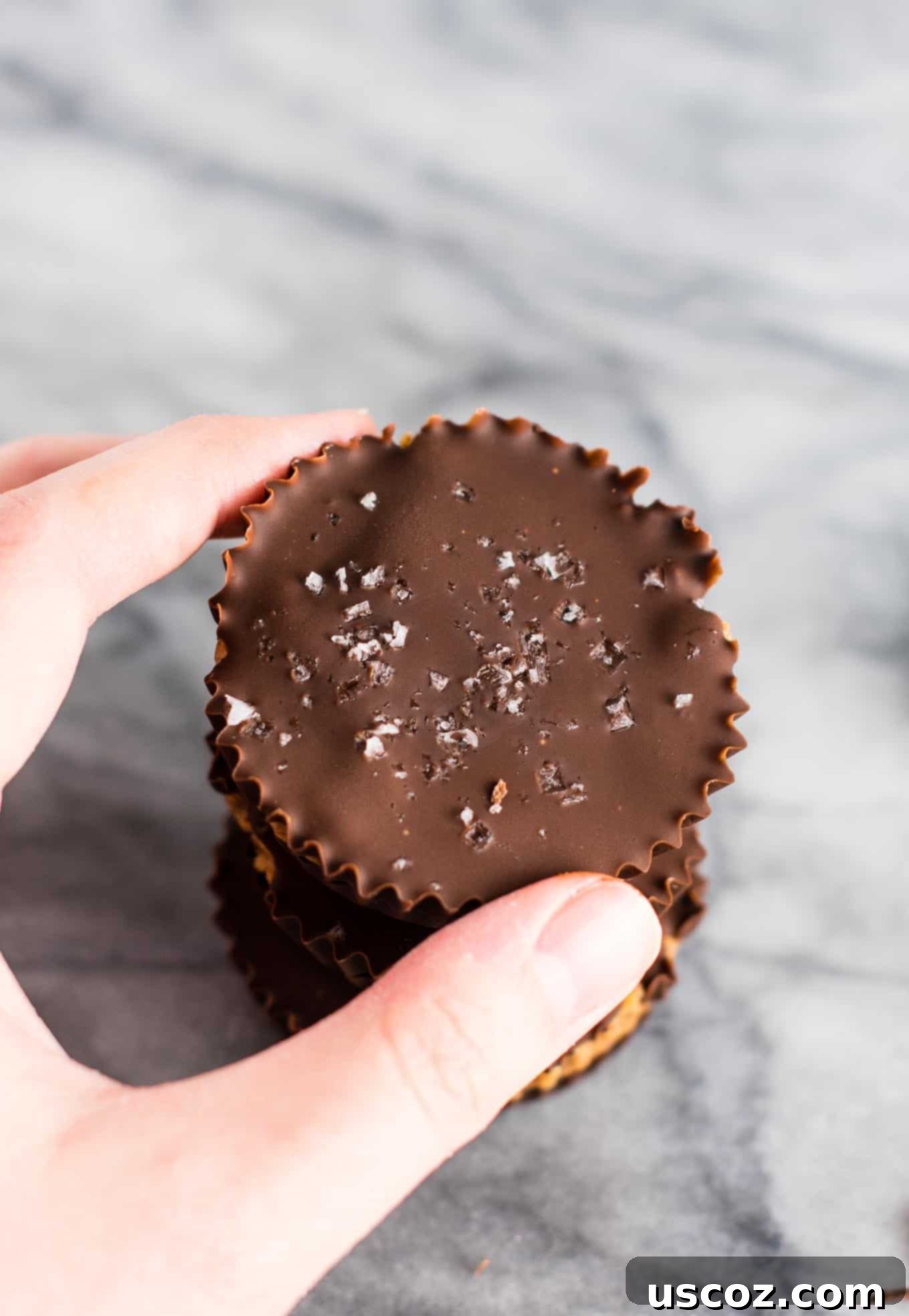 Close-up of a single chocolate almond butter cup, showing its texture and flaky sea salt topping