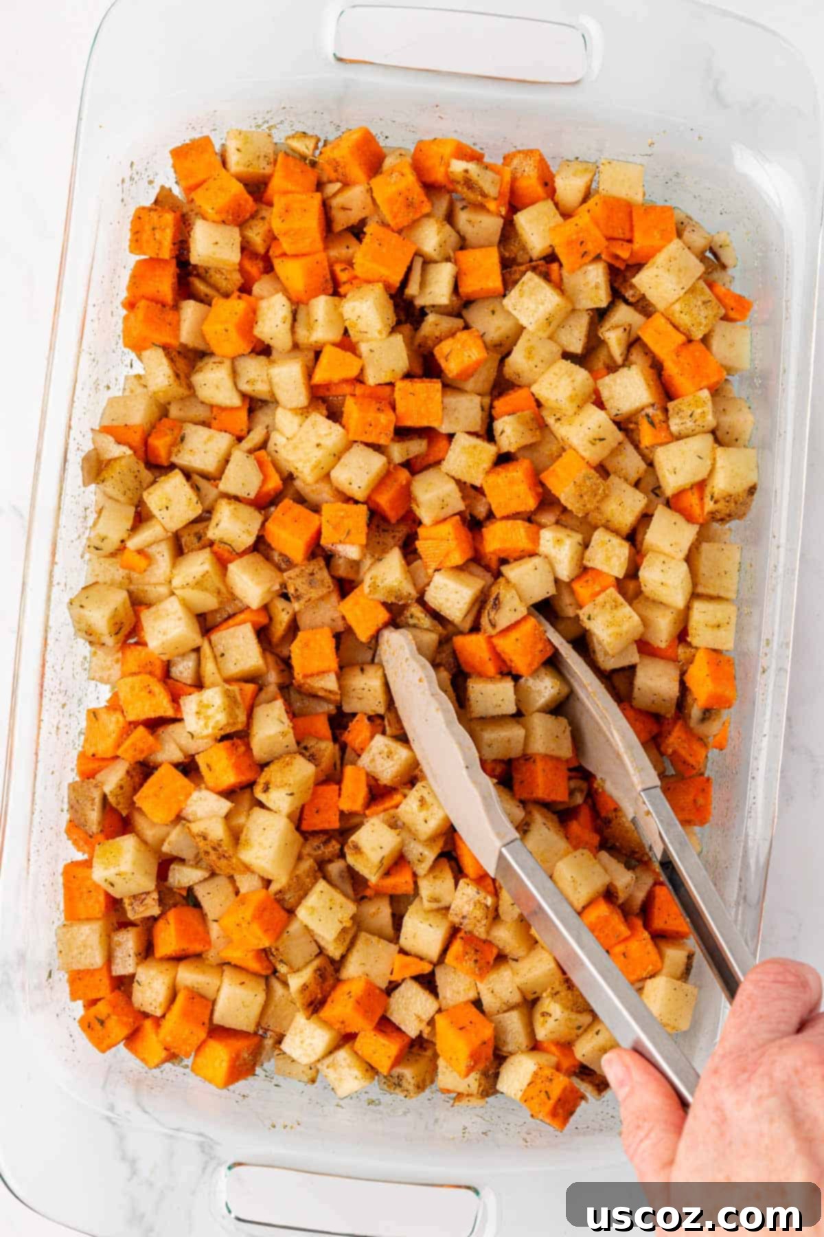 Hearty Vegan Breakfast Hash 6 Mixing spices and olive oil into potatoes in a baking dish