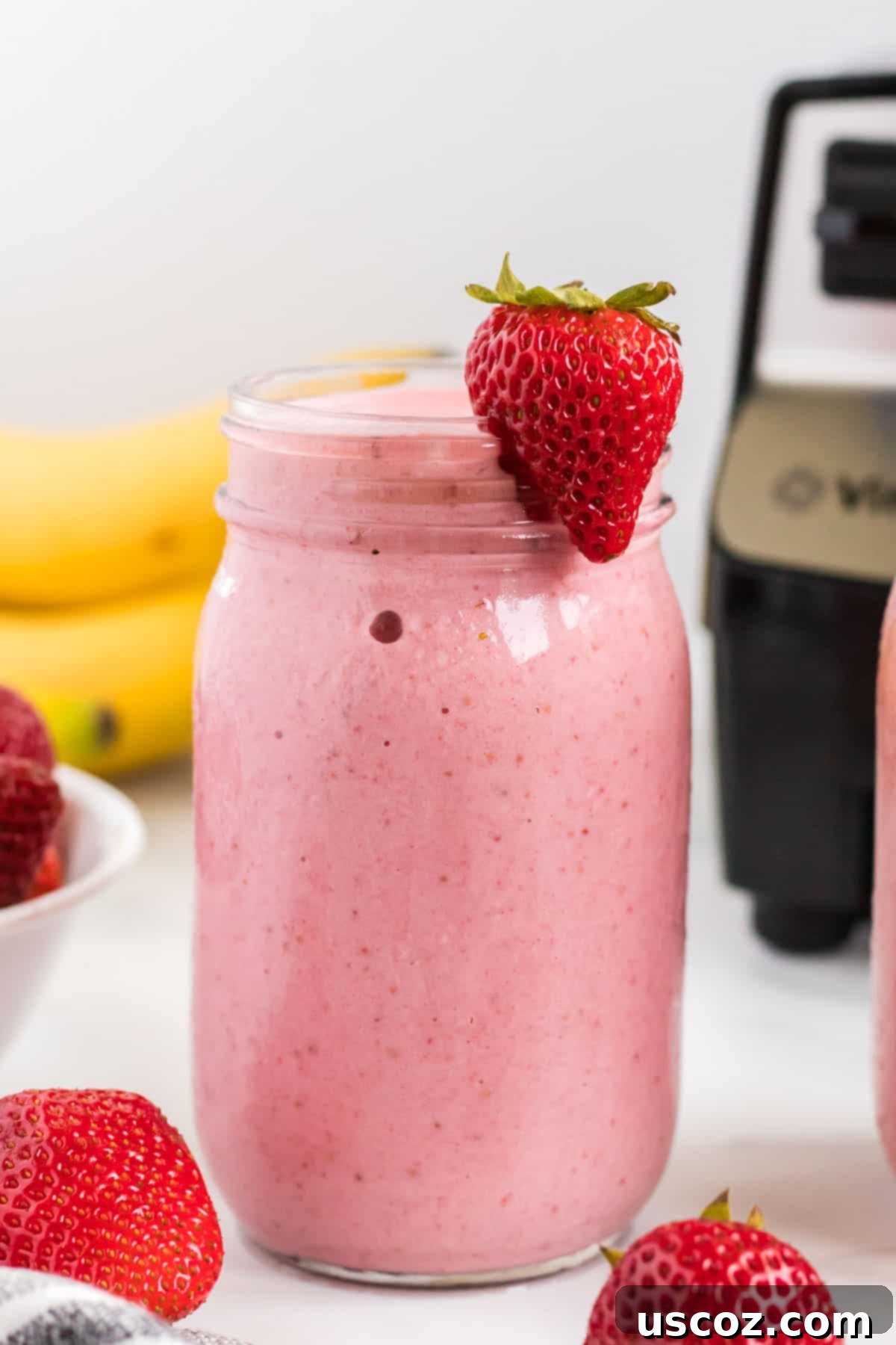 Sweet Strawberry Banana Bliss 10 strawberry banana smoothie in a mason jar with a strawberry on the rim