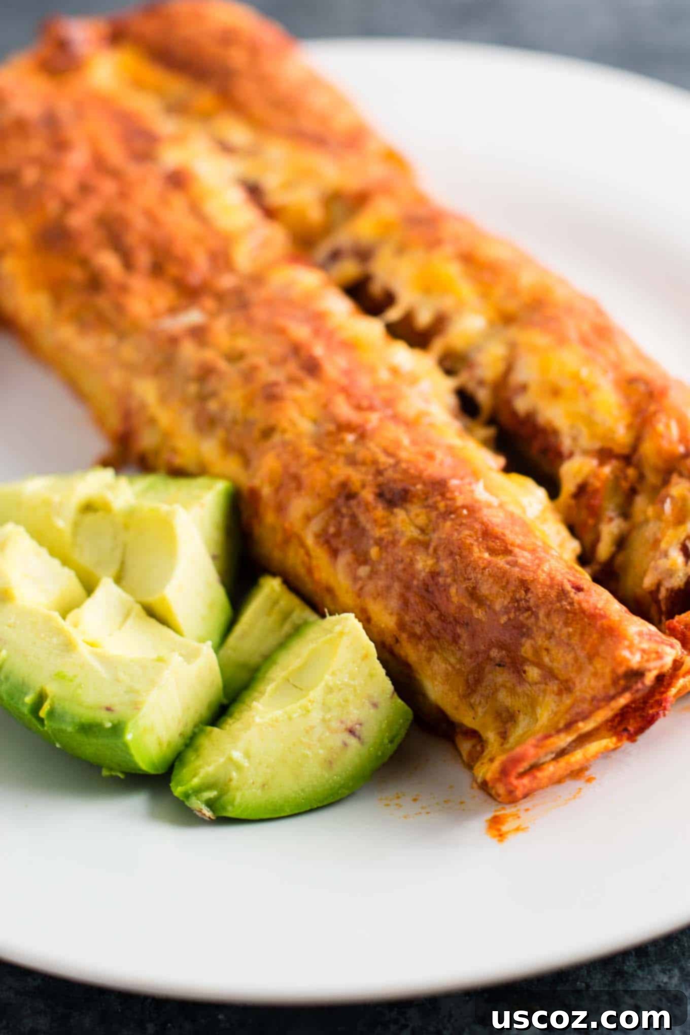 Plant-Powered Mexican Feasts 17 Close-up of baked refried bean enchiladas, covered in red sauce and melted cheese
