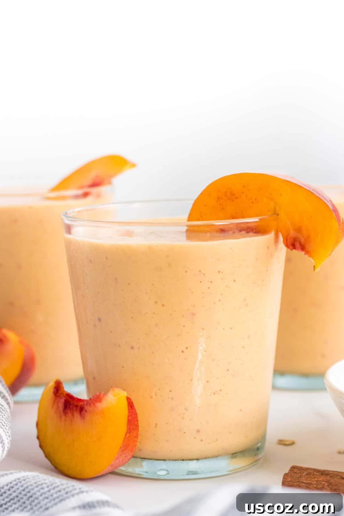 Wholesome Peach Smoothie 2 Healthy peach smoothie in a tall glass with a fresh peach slice on the rim, garnished for a refreshing look.