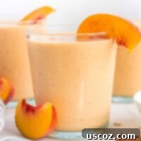 Wholesome Peach Smoothie 9 healthy peach smoothie in a glass with a peach slice on the rim