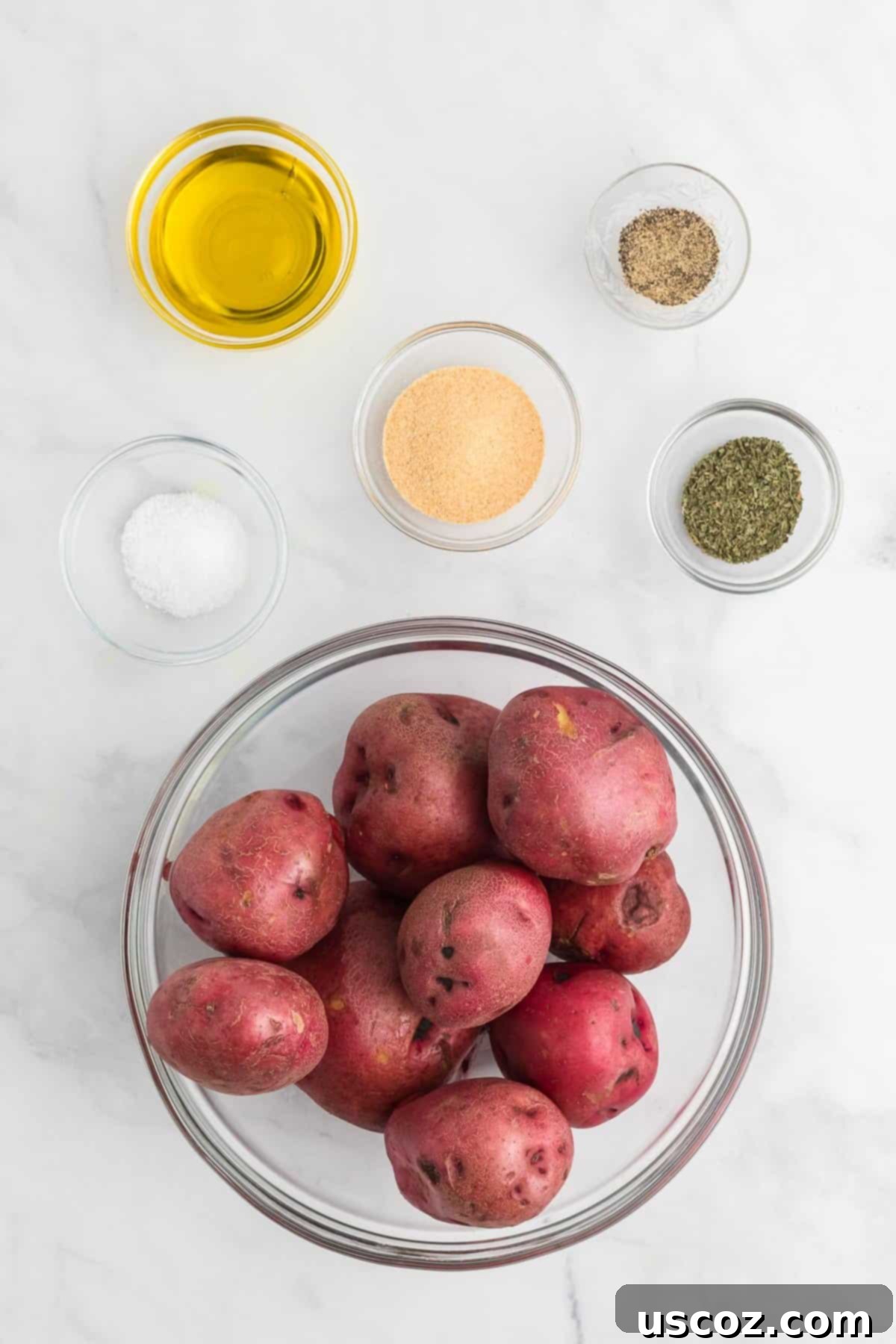 Garlic Herb Roasted Baby Red Potatoes 3 a collection of fresh ingredients needed to make roasted red potatoes, including baby red potatoes, olive oil, garlic powder, basil, salt, and pepper