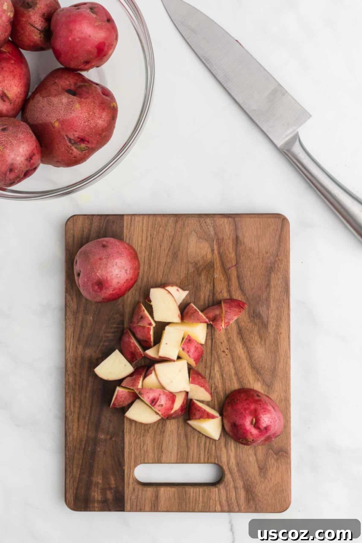 Garlic Herb Roasted Baby Red Potatoes 4 cutting red potatoes into uniform chunks on a wooden cutting board