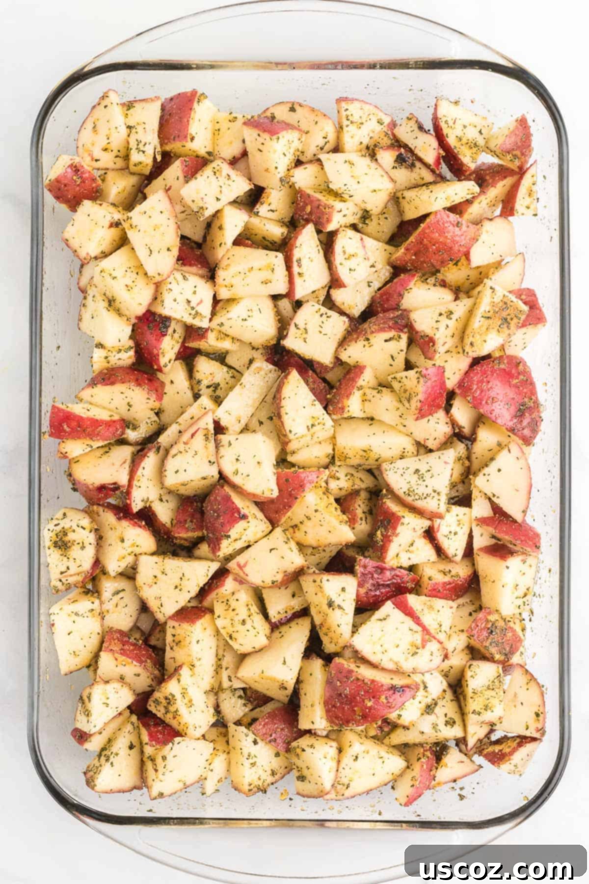 Garlic Herb Roasted Baby Red Potatoes 7 diced red potatoes mixed with spices and olive oil in a baking dish, ready for the oven