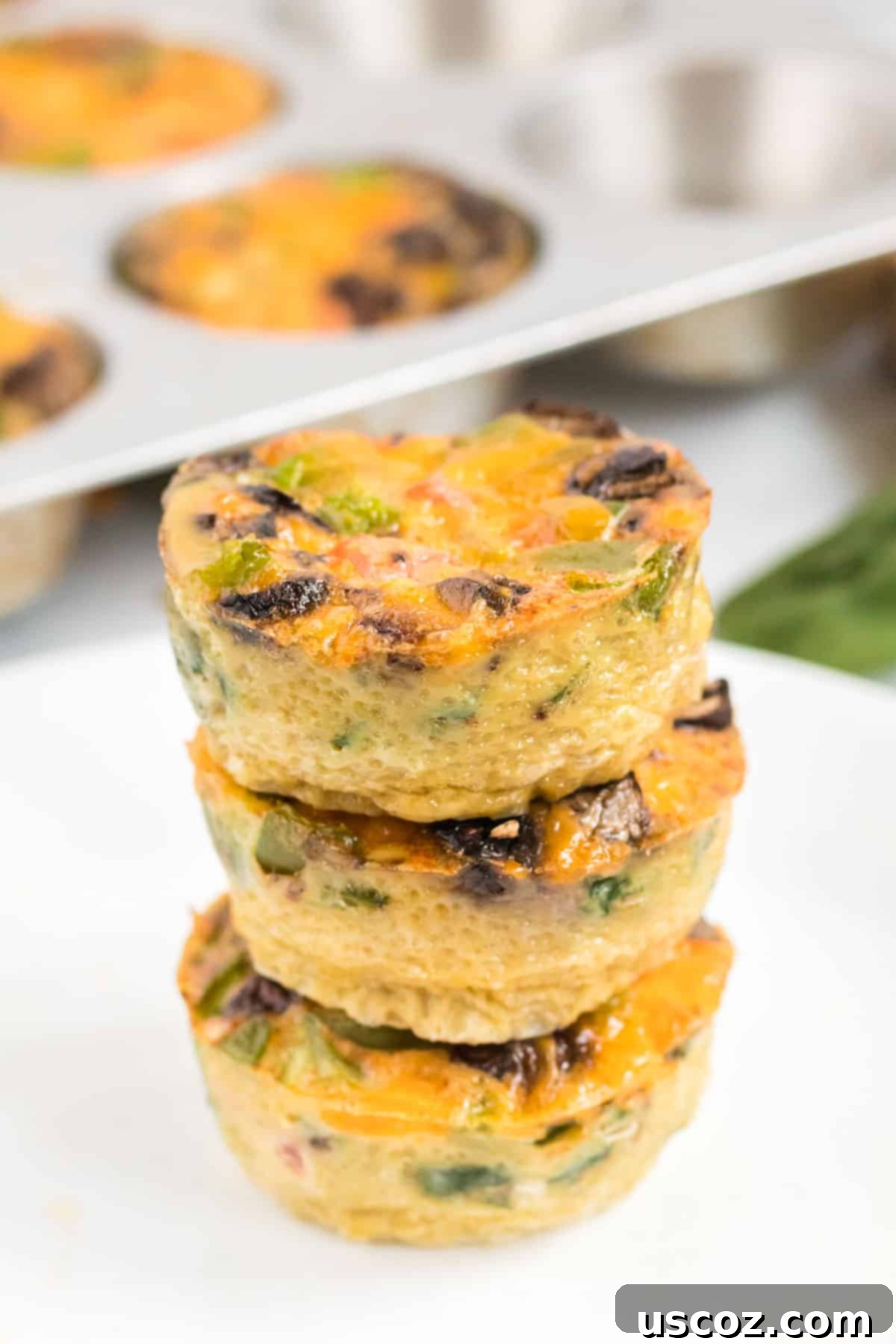 Savory Egg Muffins 3 A stack of perfectly golden-brown egg muffins, showcasing their fluffy texture and vibrant ingredients.