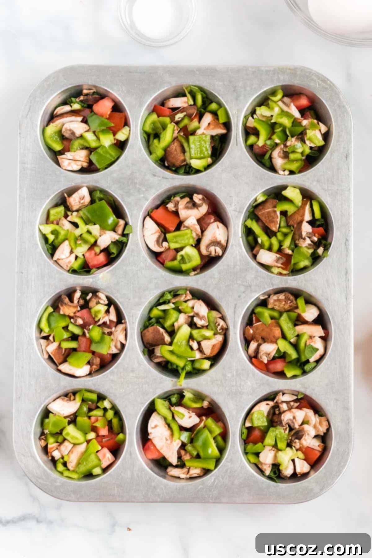 Savory Egg Muffins 5 Finely chopped vegetables distributed evenly inside a prepared muffin tin, ready for the egg mixture.