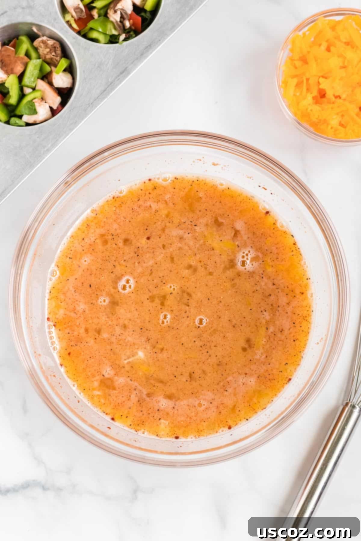 Savory Egg Muffins 6 A smooth, whisked egg batter in a clear glass bowl, seasoned and ready for pouring.