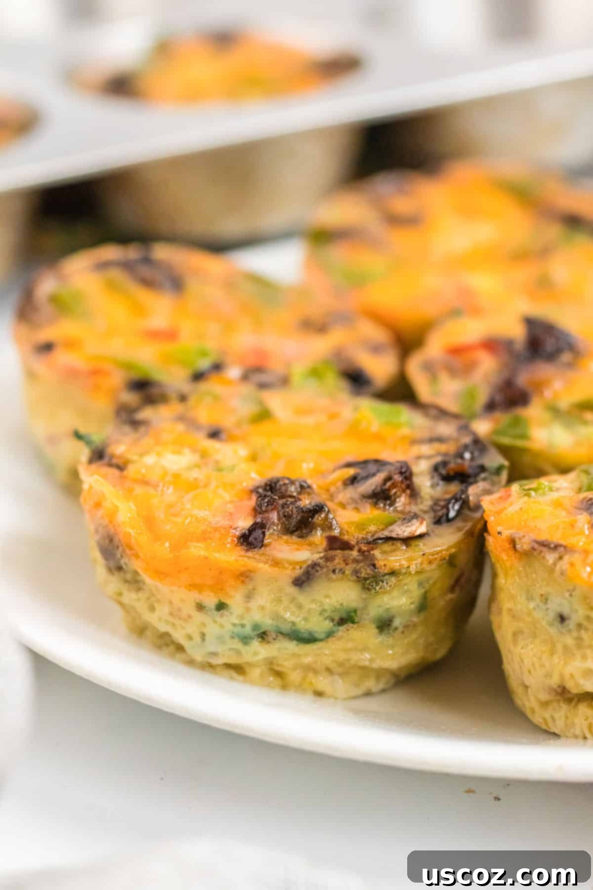 Savory Egg Muffins 9 Several egg muffins arranged artfully on a white plate, ready to be enjoyed.
