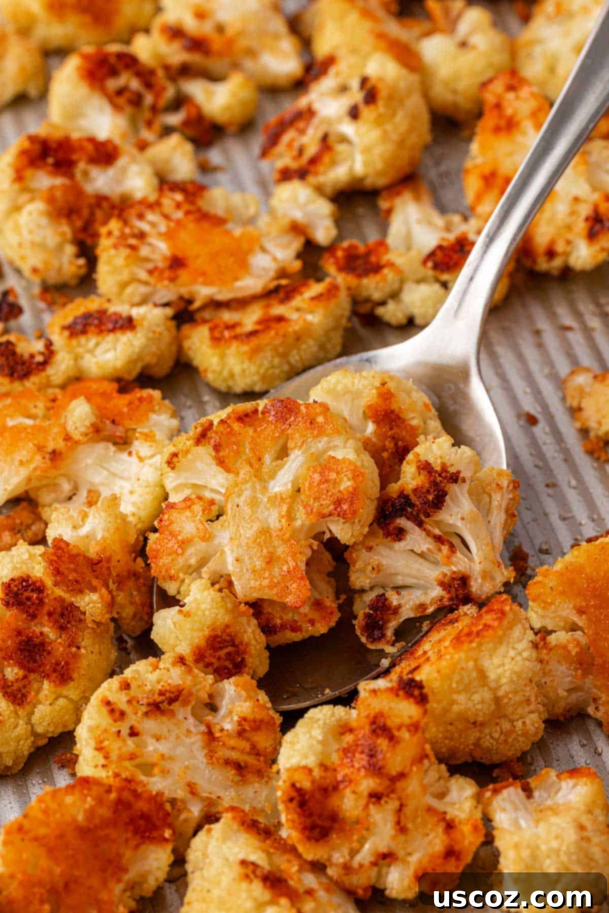 Crispy Parmesan Roasted Cauliflower 2 scooping parmesan roasted cauliflower from a baking sheet