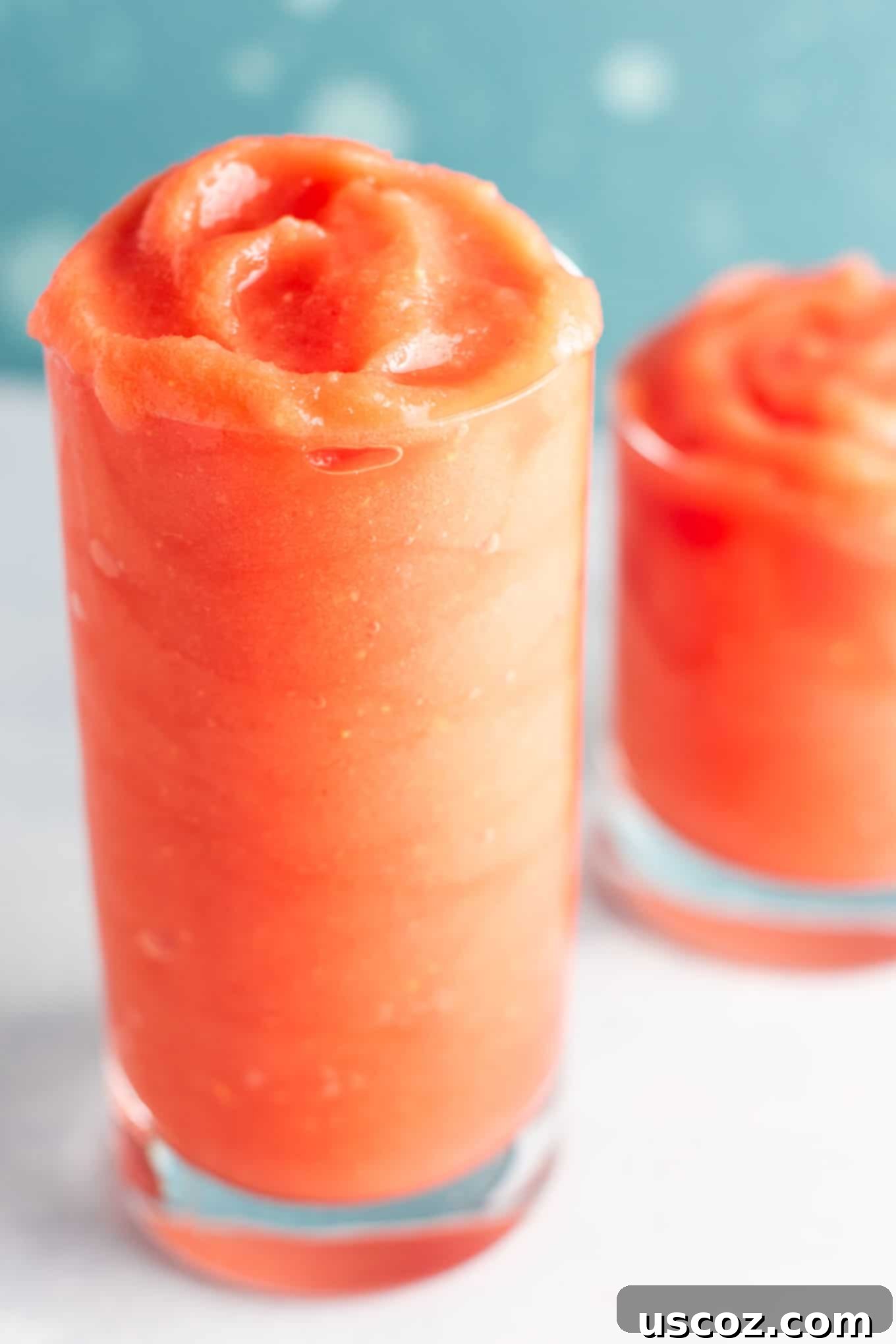 Two glasses of vibrant watermelon gin slushies on a sunny patio