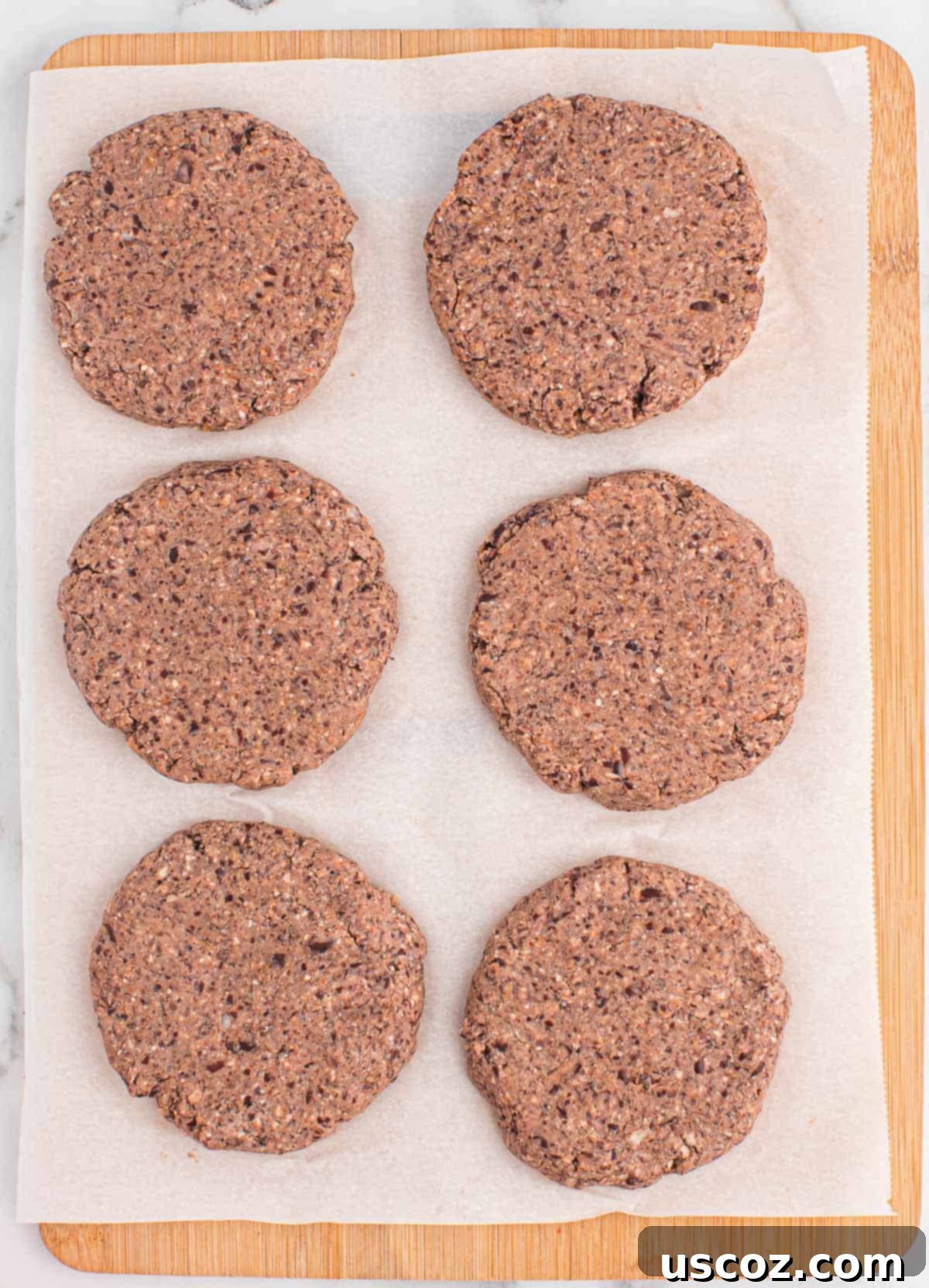 Ultimate Black Bean Burgers 8 perfectly shaped black bean burgers resting on parchment paper, ready to be cooked