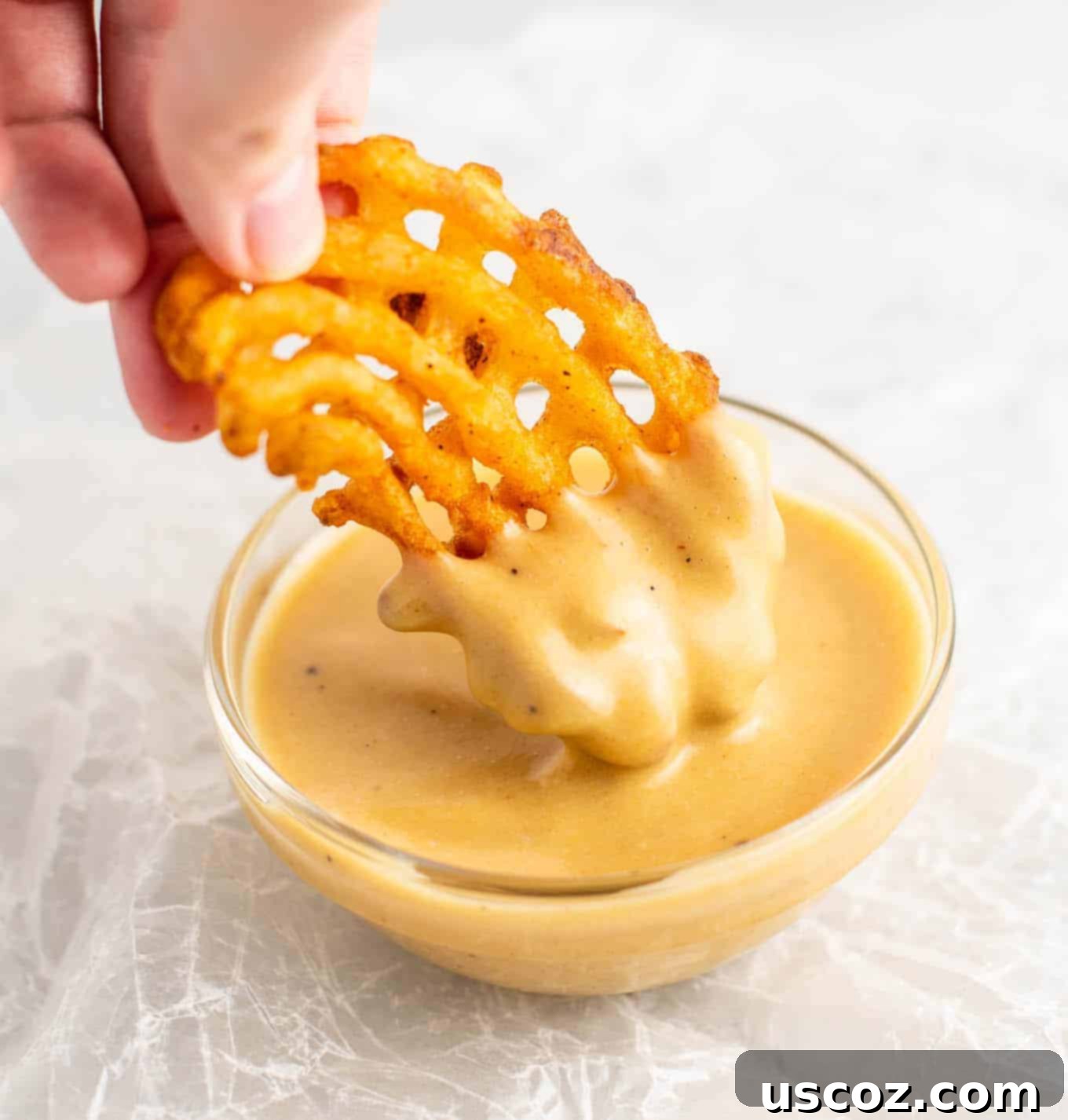 Golden Chickpea Poppers 8 Crispy waffle fries dipped into a bowl of golden Chick-fil-A style sauce, showcasing a delicious pairing.