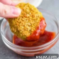 Golden Chickpea Poppers 10 Crispy chickpea nugget being dipped in ketchup, showcasing its delicious appeal.