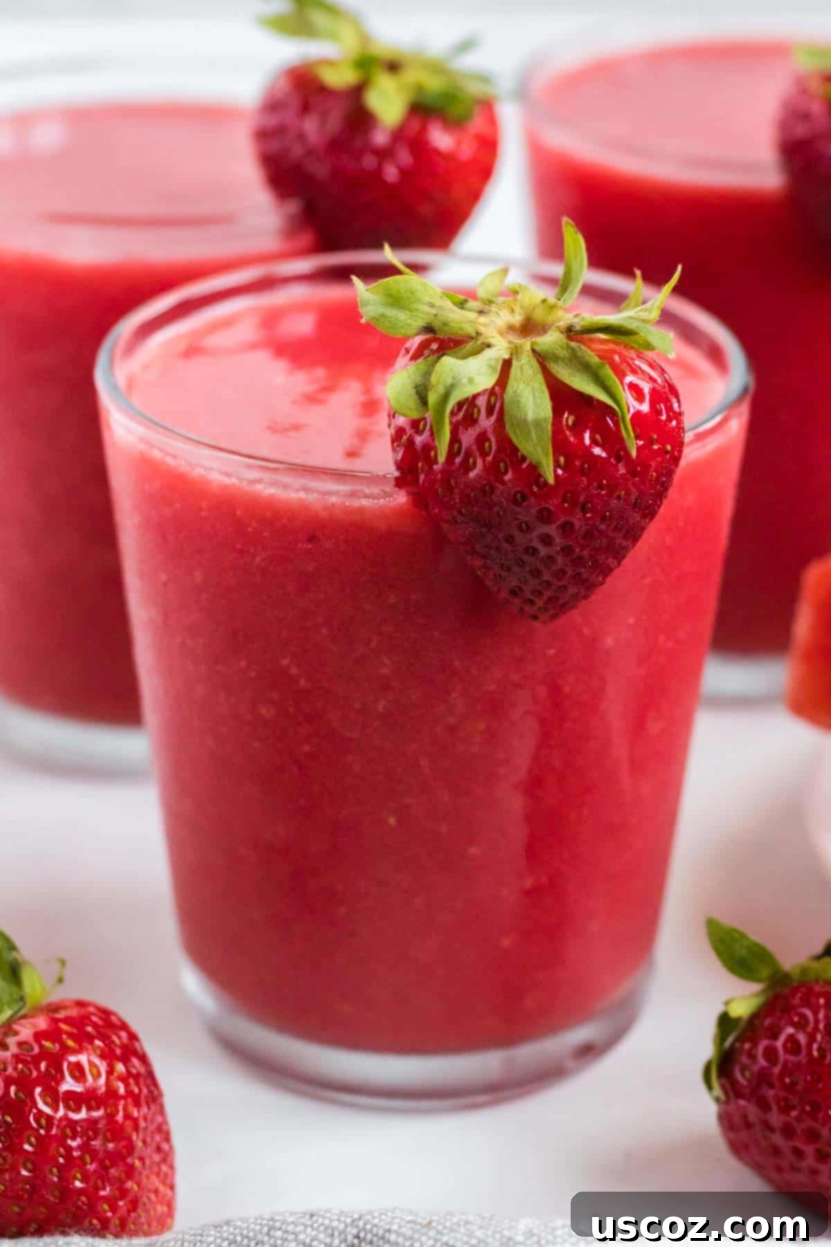 Sweet Summer Smoothie Sensation 2 strawberry watermelon smoothie in a clear glass with a strawberry on the rim