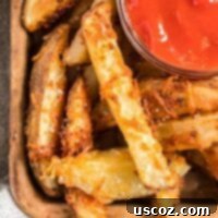 Garlic Parmesan Baked Potato Wedges 11 A bowl of crispy baked parmesan potato wedges with a side of ketchup, perfectly golden and ready to be served as an appetizer or a delightful side dish.