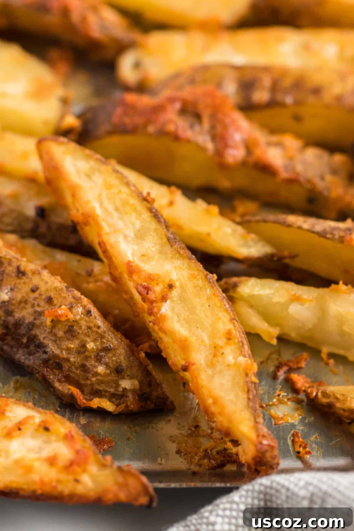 Garlic Parmesan Baked Potato Wedges 3 Close-up image of a single perfectly crispy oven baked garlic parmesan potato wedge, showcasing its golden-brown, textured exterior and flaky interior, ready to be enjoyed.