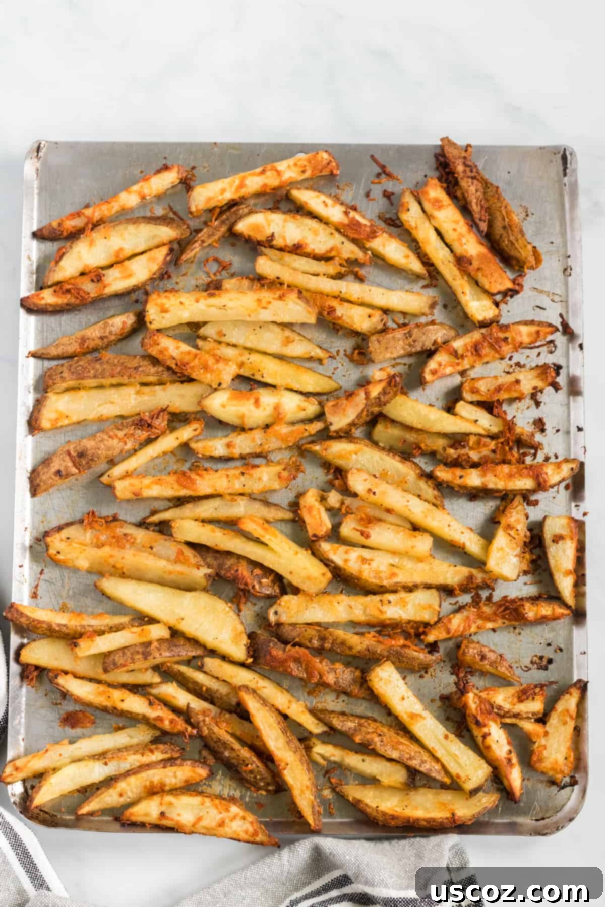 Garlic Parmesan Baked Potato Wedges 6 A baking sheet filled with golden-brown, oven baked garlic parmesan potato wedges, showcasing their beautifully crispy parmesan edges and perfect roast, cooling slightly after being taken out of the oven.