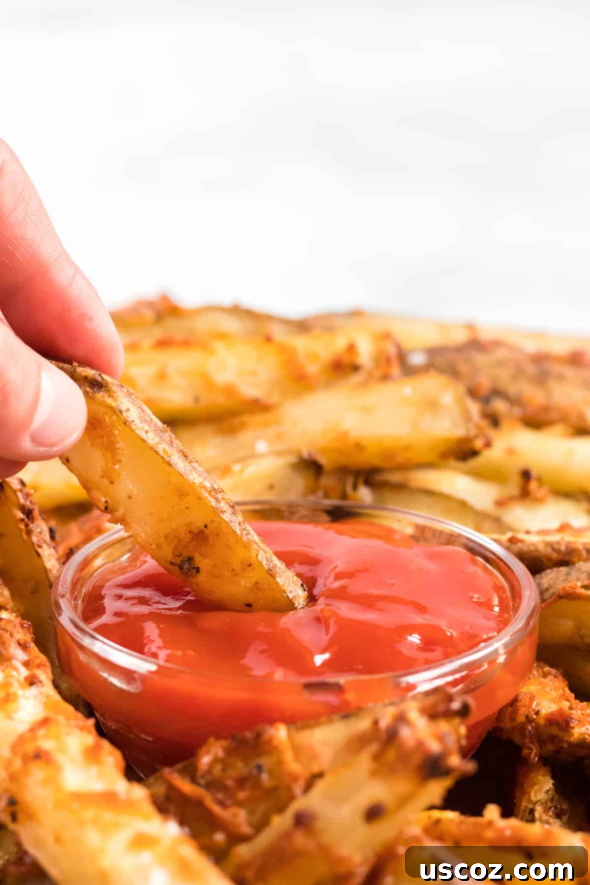 Garlic Parmesan Baked Potato Wedges 8 Another enticing shot of a golden parmesan crusted potato wedge being dipped into ketchup, emphasizing the perfect texture and delicious pairing for this homemade recipe.