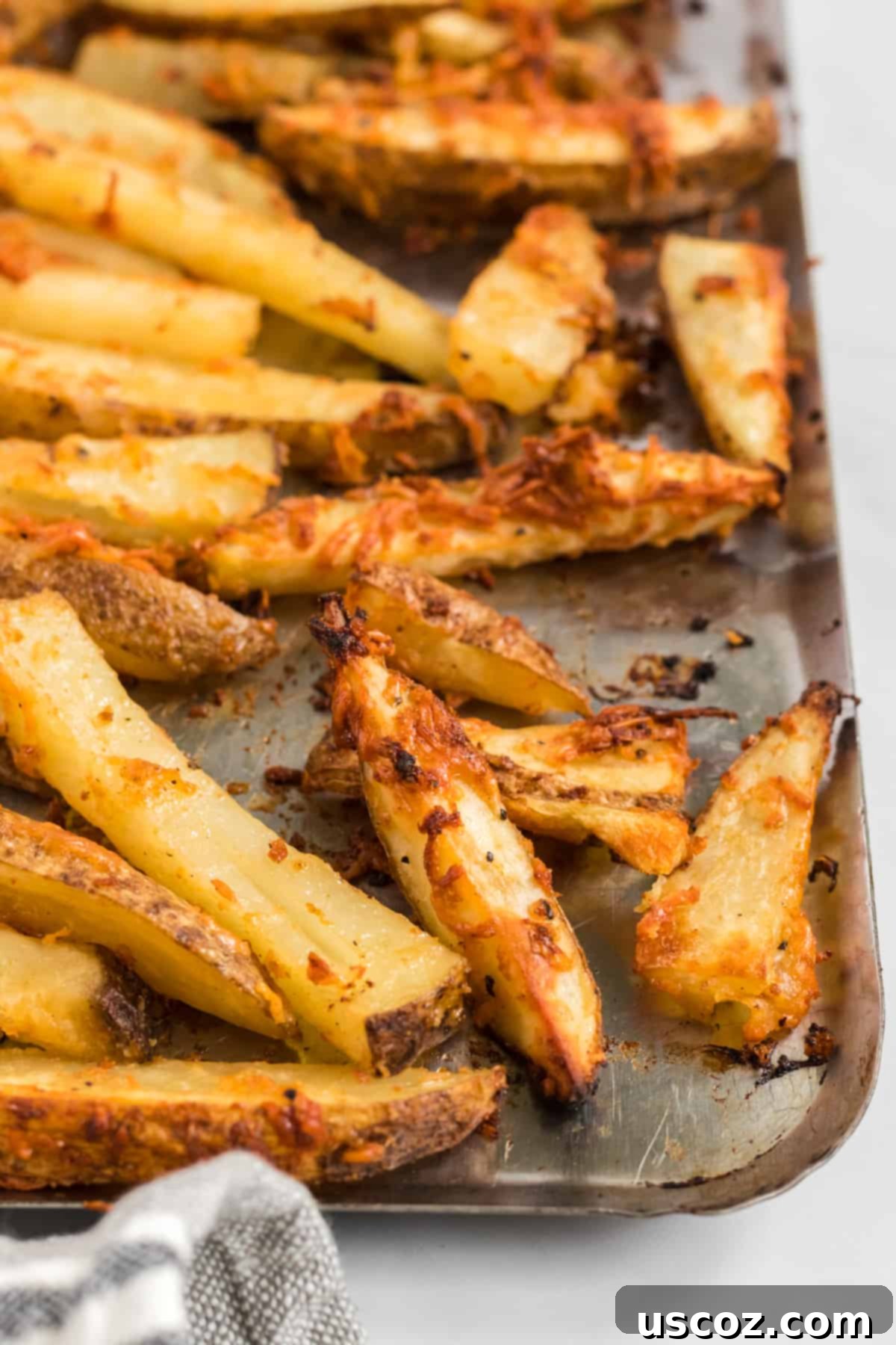 Garlic Parmesan Baked Potato Wedges 9 A large batch of perfectly golden and crispy parmesan crusted potato wedges, generously seasoned and glistening, spread out evenly on a baking sheet after being roasted in the oven.